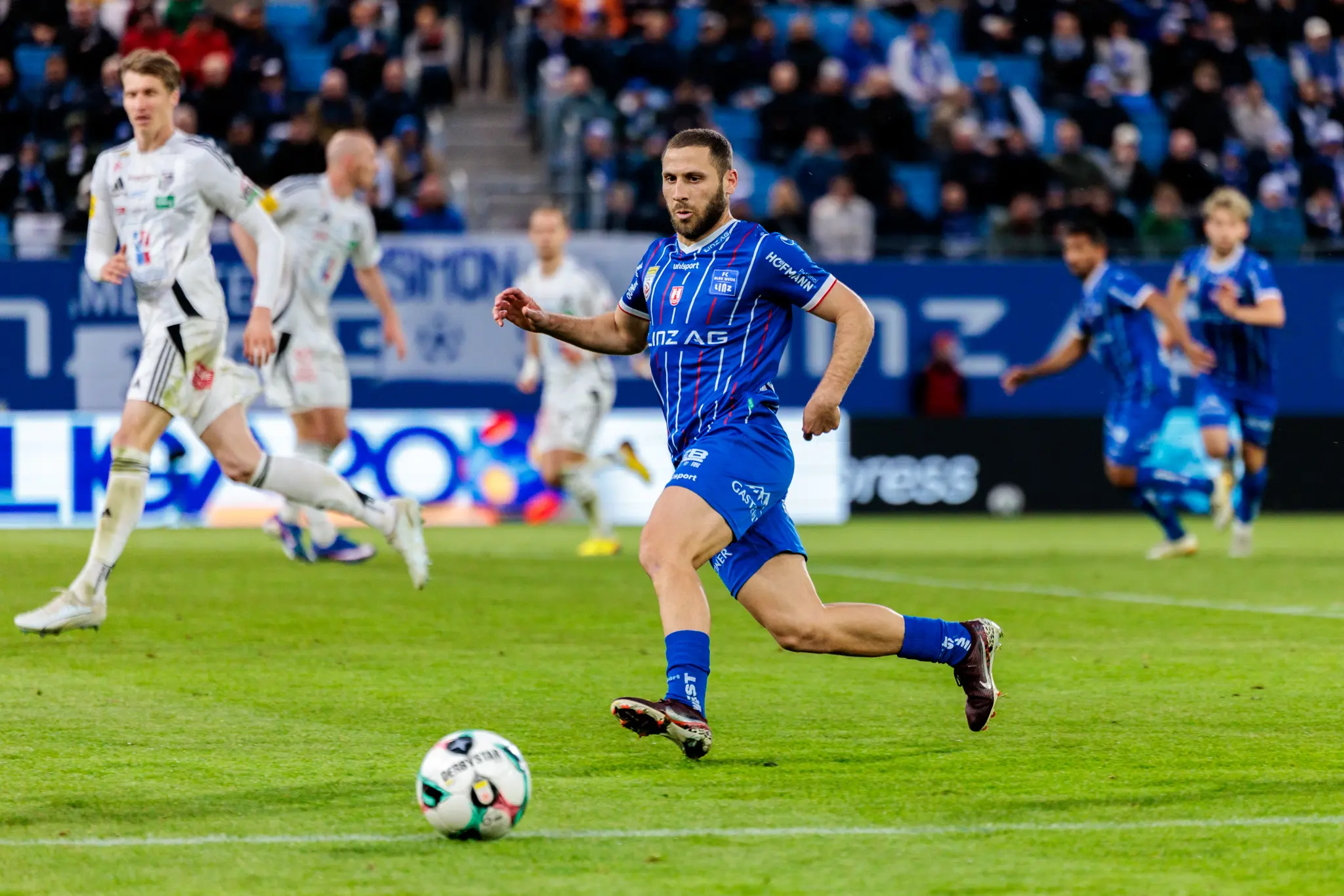 Ein Spieler von Blau-Weiß Linz führt einen dynamischen Dribbling-Angriff gegen den Wolfsberger AC aus