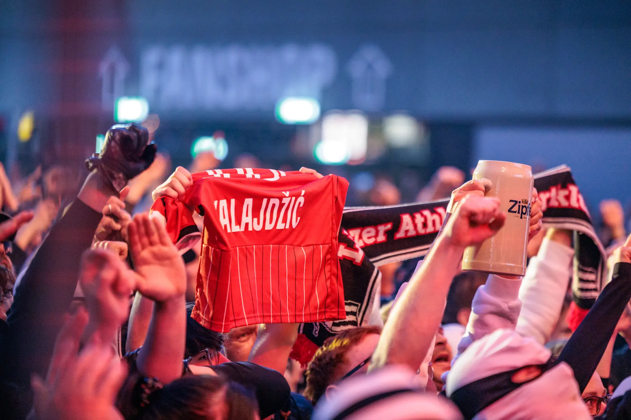 Ein begeisterter Fan präsentiert ein rotes LASK-Trikot mit dem Aufdruck „KALAJDŽIĆ“ während der Meisterfeier in Linz