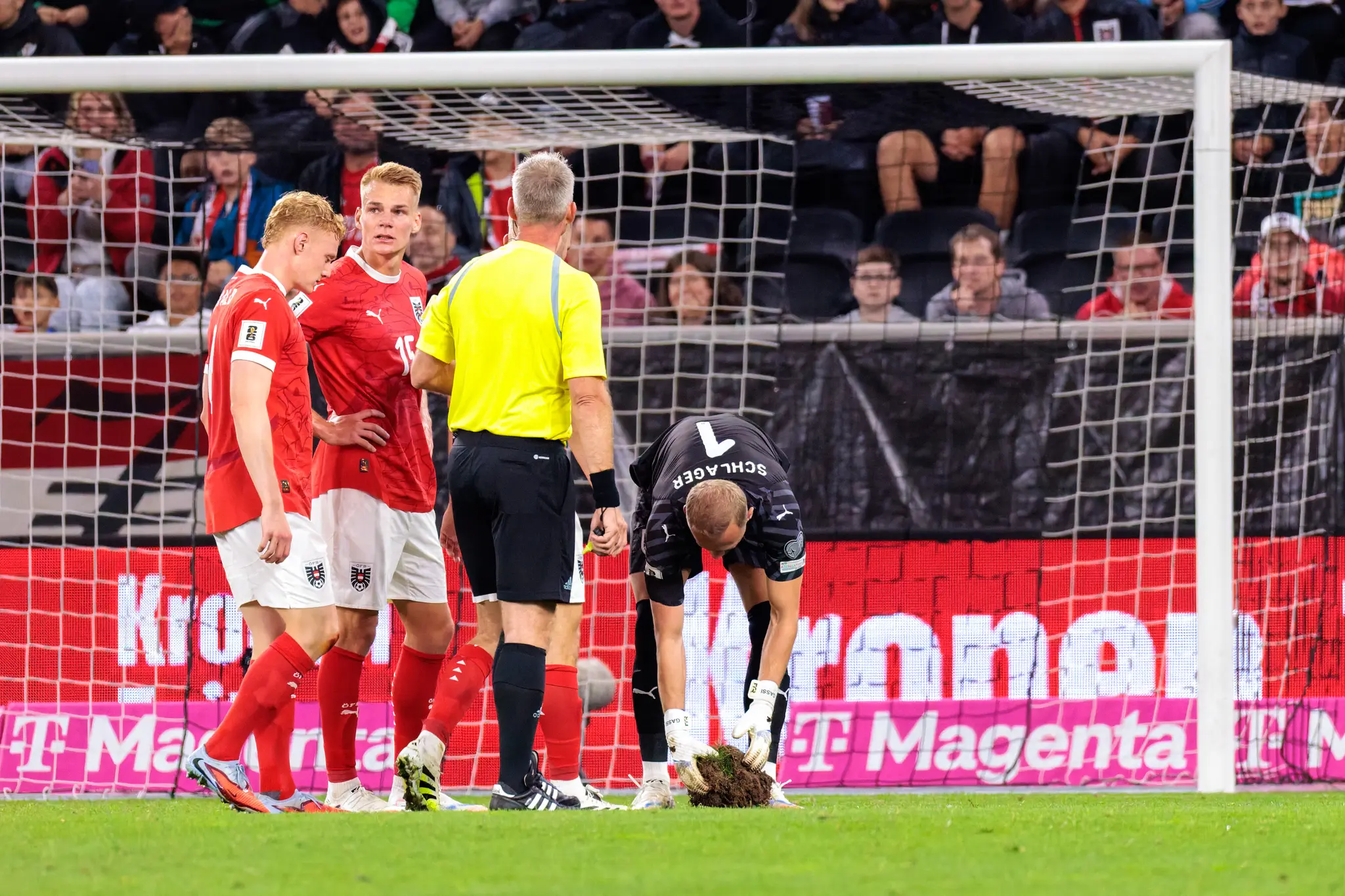 Österreichs Torwart Alexander Schlager (Nummer 1) inspiziert den Schaden am Rasen während des WM-Qualifikationsspiels gegen Zypern, beobachtet von vom Schiedsrichter und mehreren österreichischen Spielern