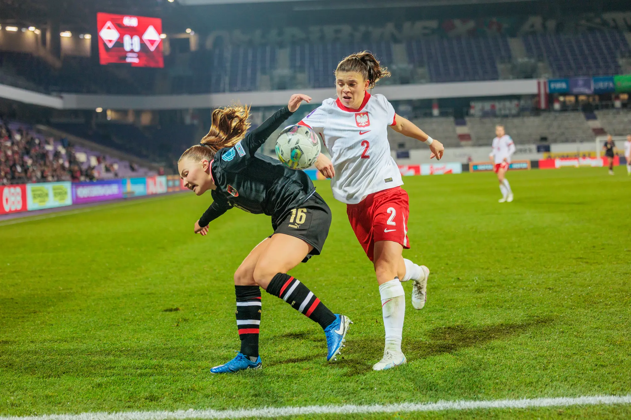 Zwei Frauenfußballerinnen, eine aus Österreich und eine aus Polen, kämpfen im Stadion um den Ball 