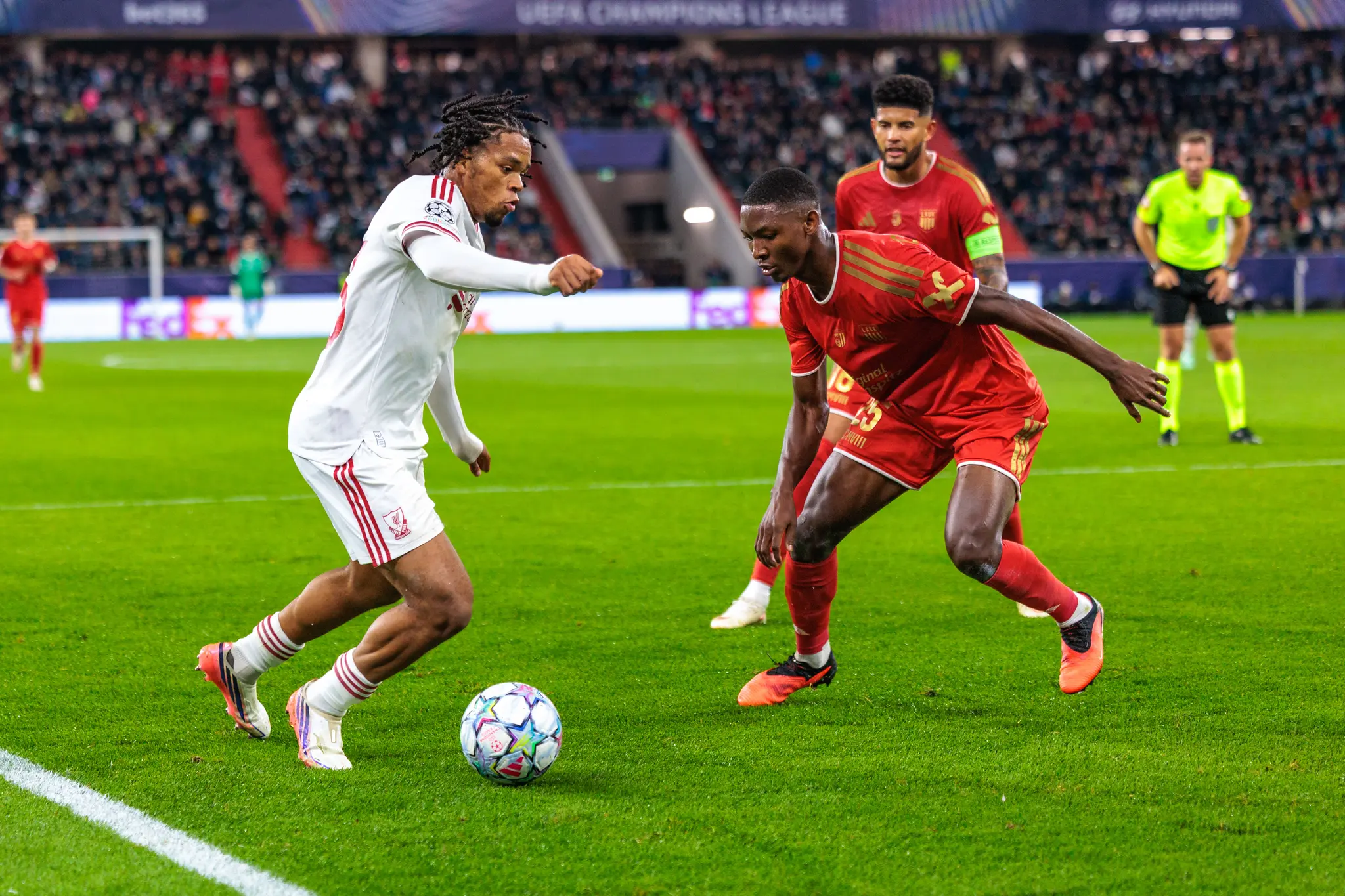Ein Liverpooler Spieler führt den Ball an der Seitenlinie, LASK-Verteidiger Yvan Dibango (25) greift ihn an, dahinter läuft ein LASK-Spieler mit Kapitänsbinde.