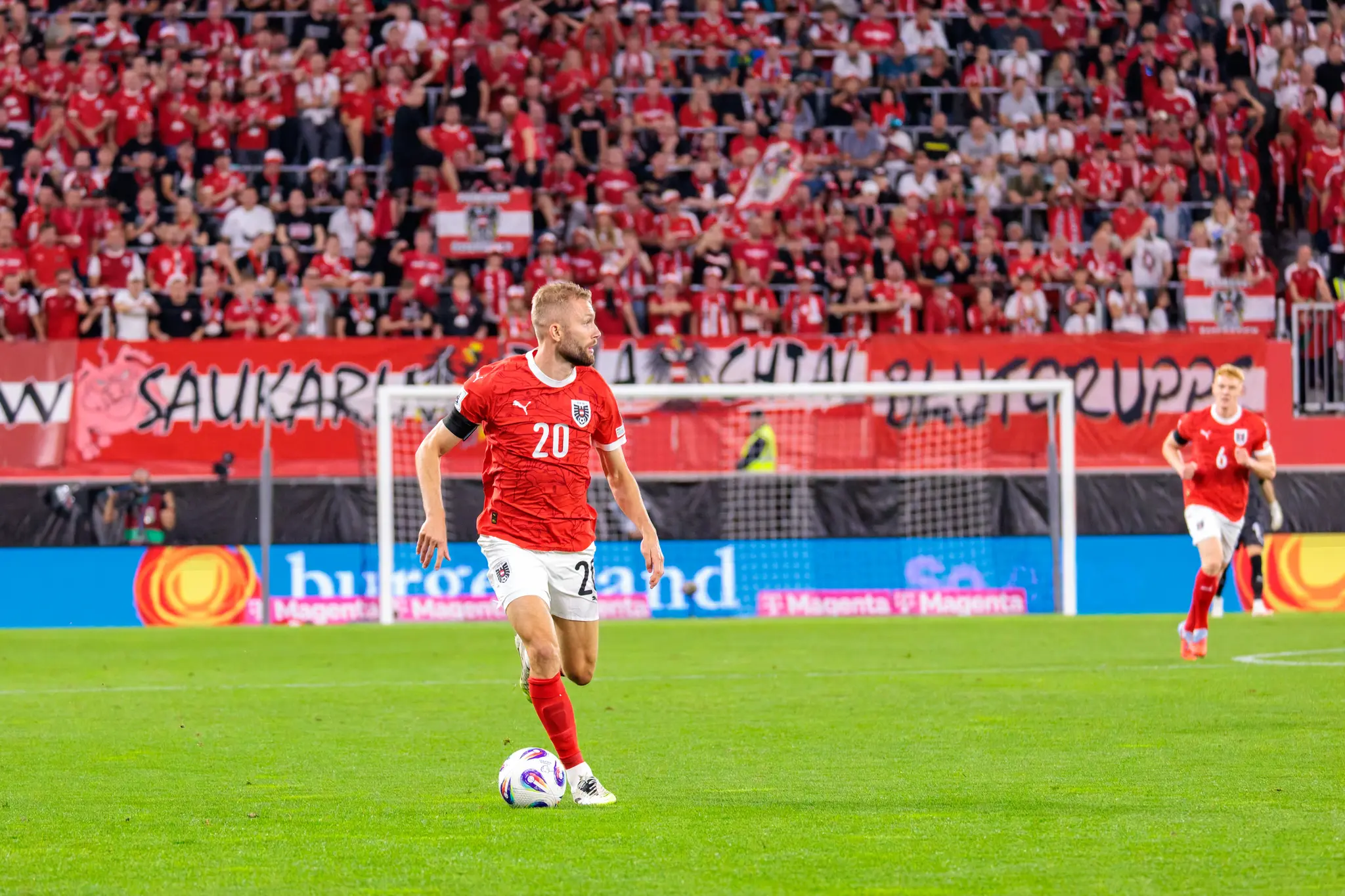 Der österreichische Nationalspieler Konrad Laimer mit der Trikotnummer 20 dribbelt den Fußball auf dem Spielfeld während des WM-Qualifikationsspiels gegen Zypern vor einer unscharfen Zuschauerkulisse