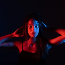 Eine junge Frau wird von rotem und blauem Licht beleuchtet, das ihr Gesicht dramatisch in zwei kontrastierende Hälften teilt lens: RF35mm F1.8 MACRO IS STM