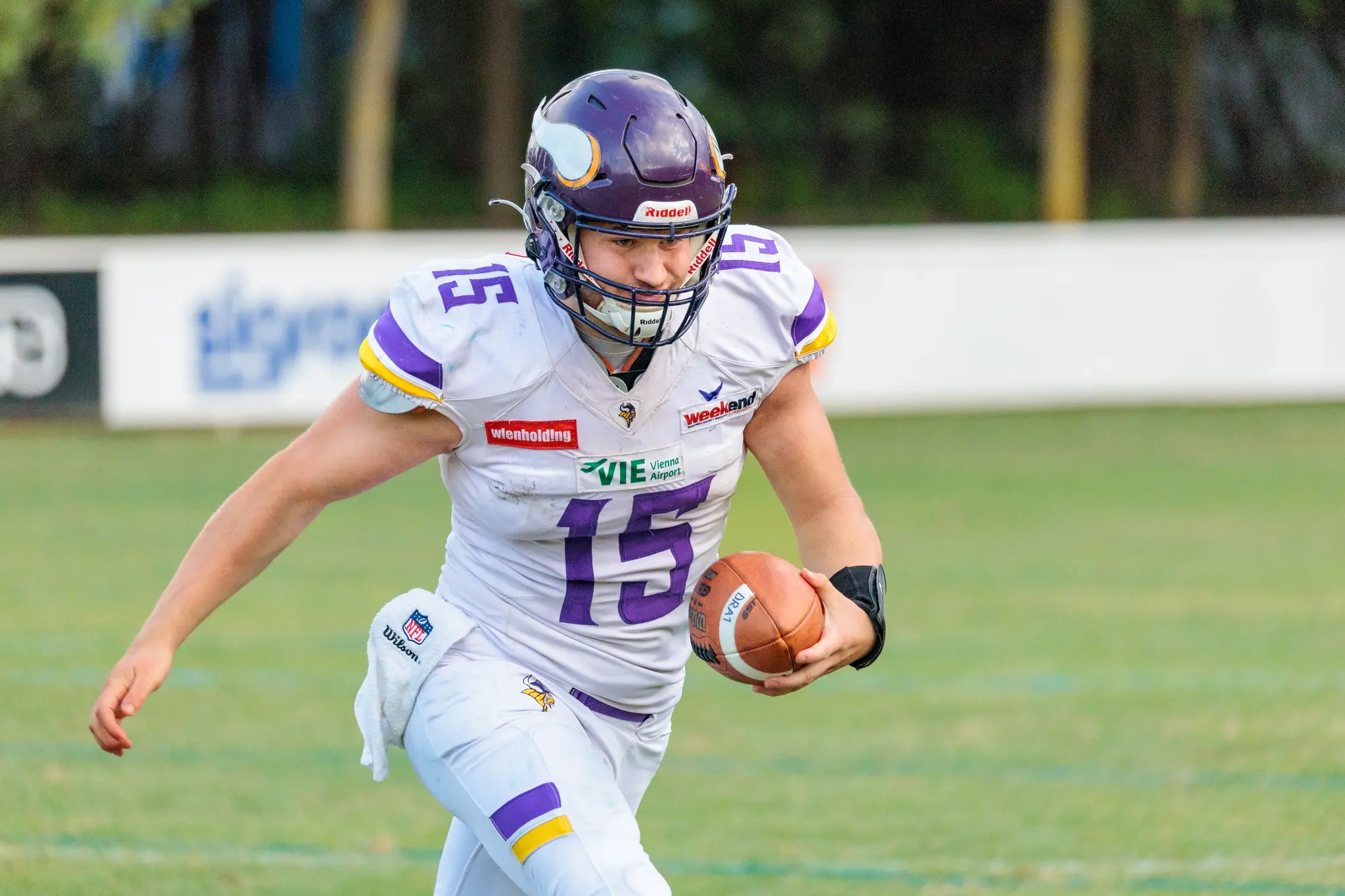 Vienna Vikings Quarterback im weißen Trikot mit Purple sucht einen Pass unter starkem Druck der Danube Dragons-Defense in grünen Trikots – AFL-Playoff 2026