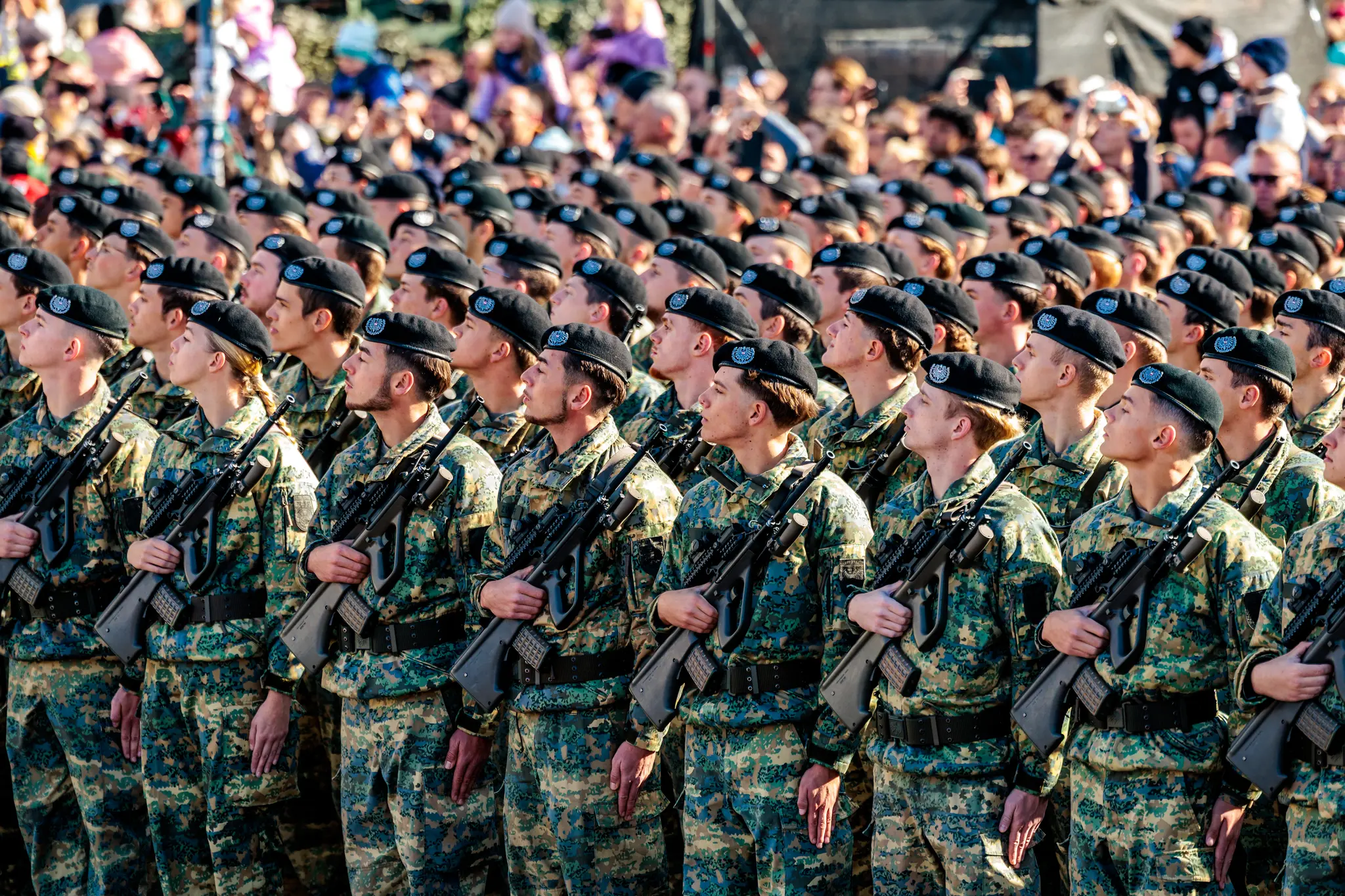 Rekrutinnen und Rekruten in Tarnuniform und schwarzen Baretten stehen mit Sturmgewehren in Reih und Glied bei der Angelobung am Heldenplatz.