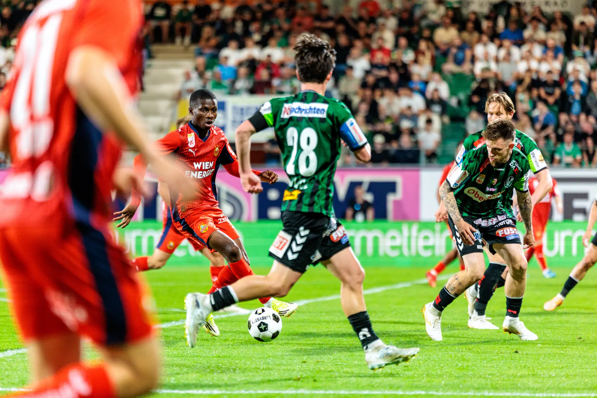 Ein Spieler des Rapid Wien behauptet den Ball in einem intensiven Laufduell während des Bundesliga-Playoff-Spiels gegen den SV Ried