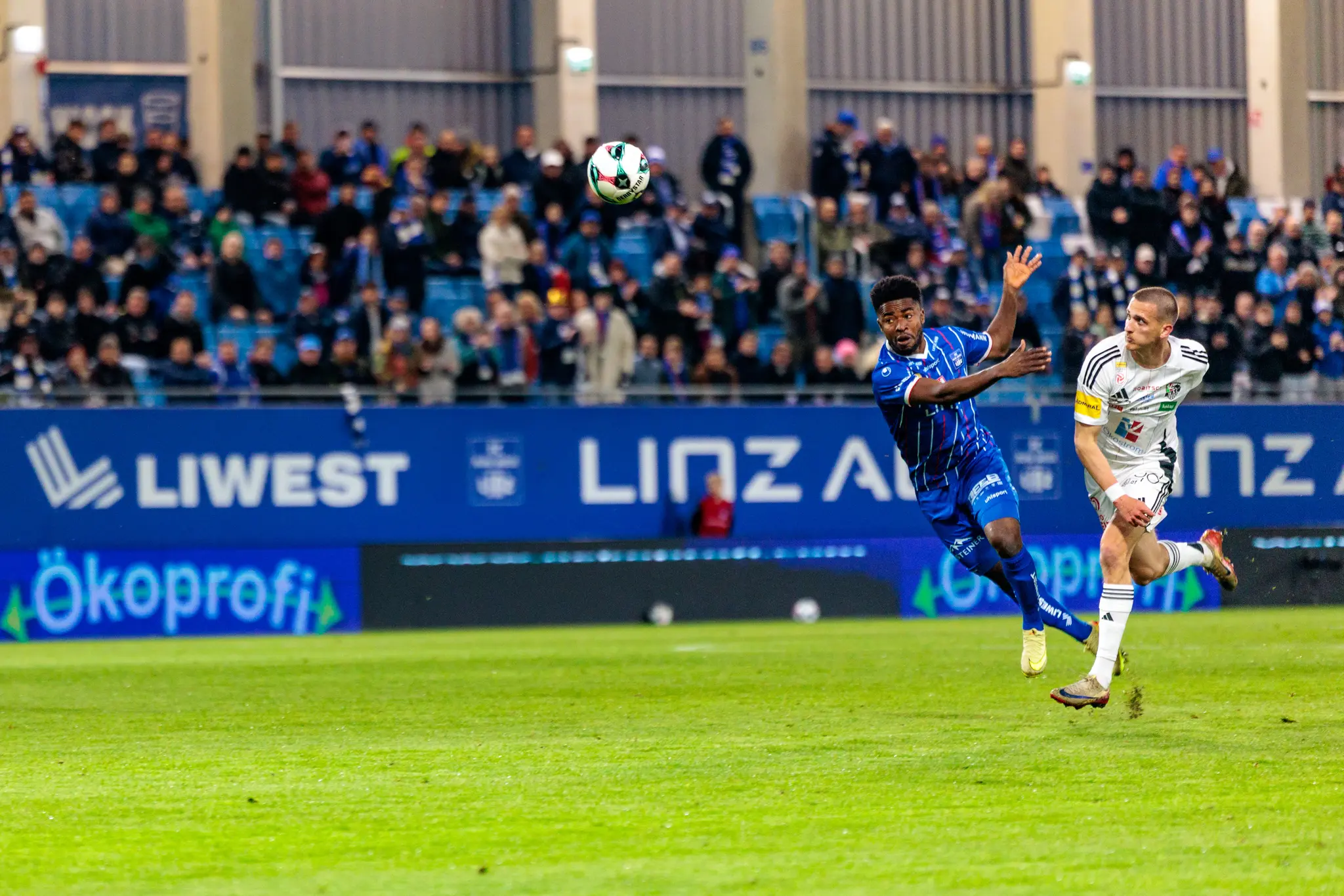 Ein Spieler von Blau-Weiß Linz kämpft in einem intensiven Zweikampf um den Kopfball gegen einen Gegenspieler des Wolfsberger AC