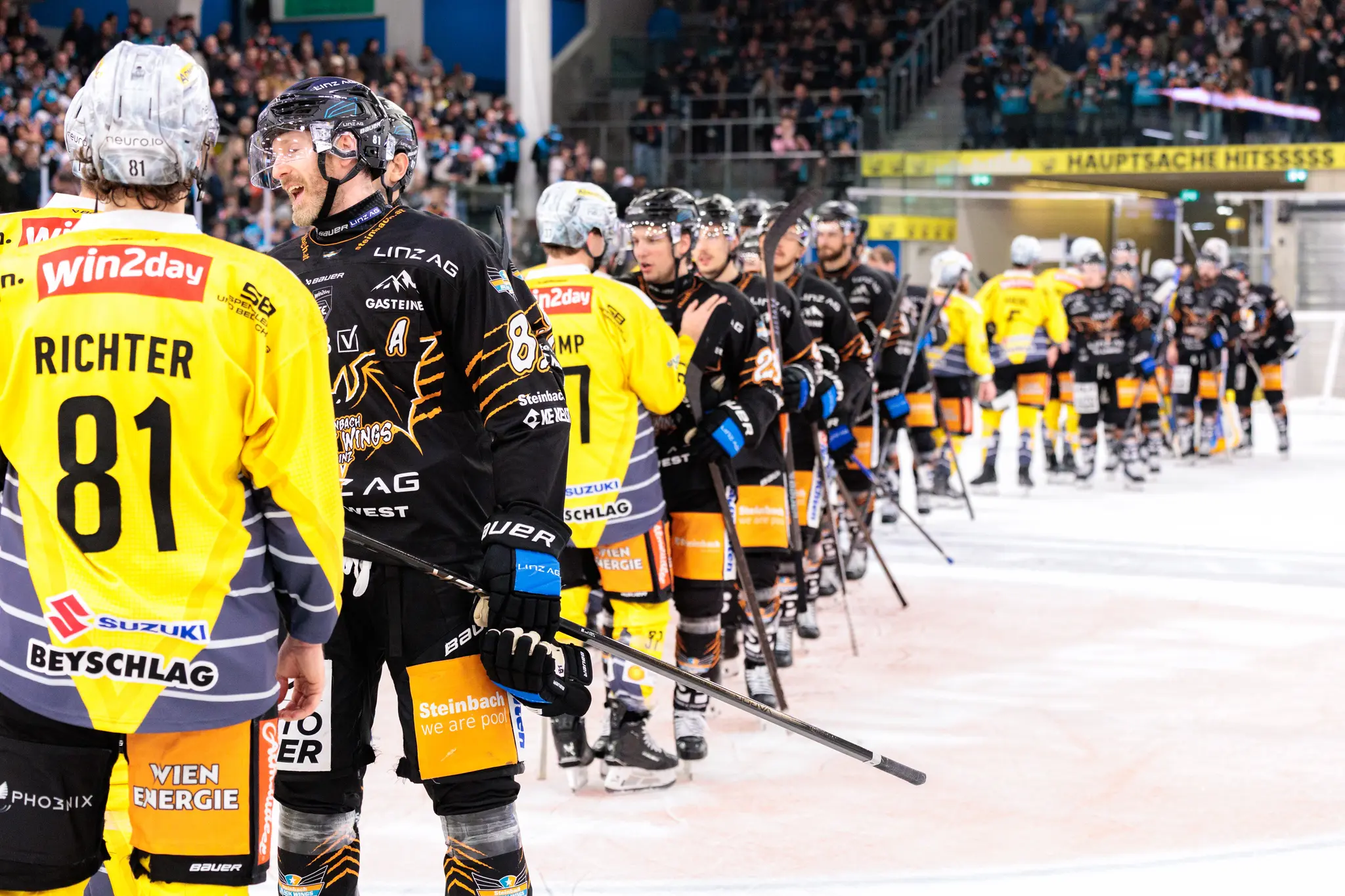 Eishockeyspieler Richter mit der Rückennummer 81 im gelben Trikot unterhält sich mit einem Spieler im schwarzen Trikot auf dem Eis nach einem Eishockeyspiel