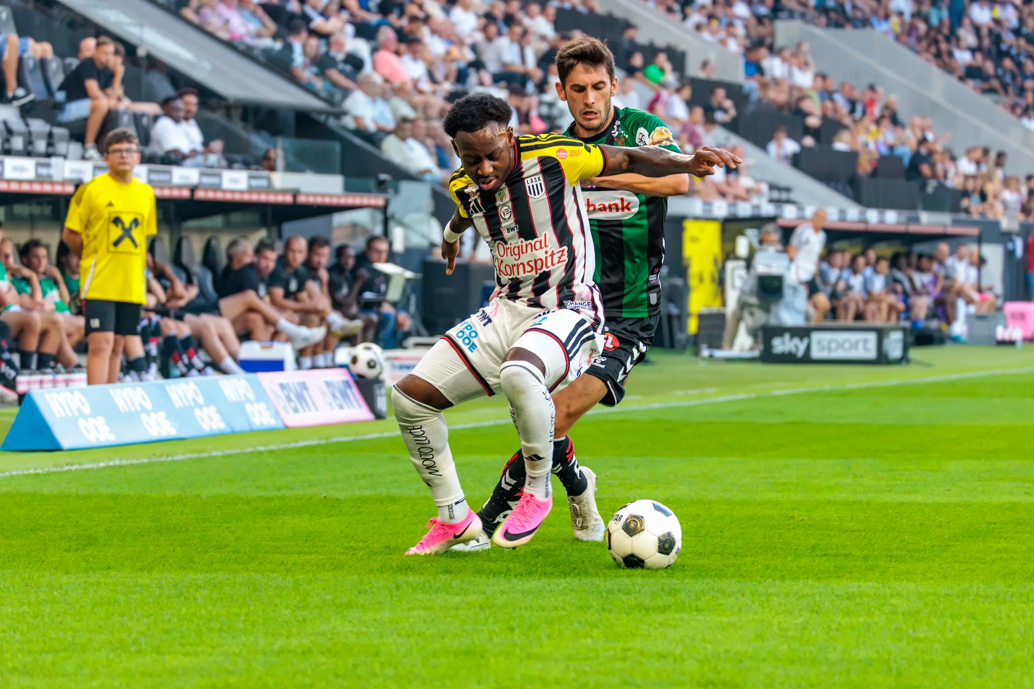 Ein LASK-Spieler schirmt den Ball an der Seitenlinie mit dem Körper ab, ein Ried-Spieler drückt von hinten nach