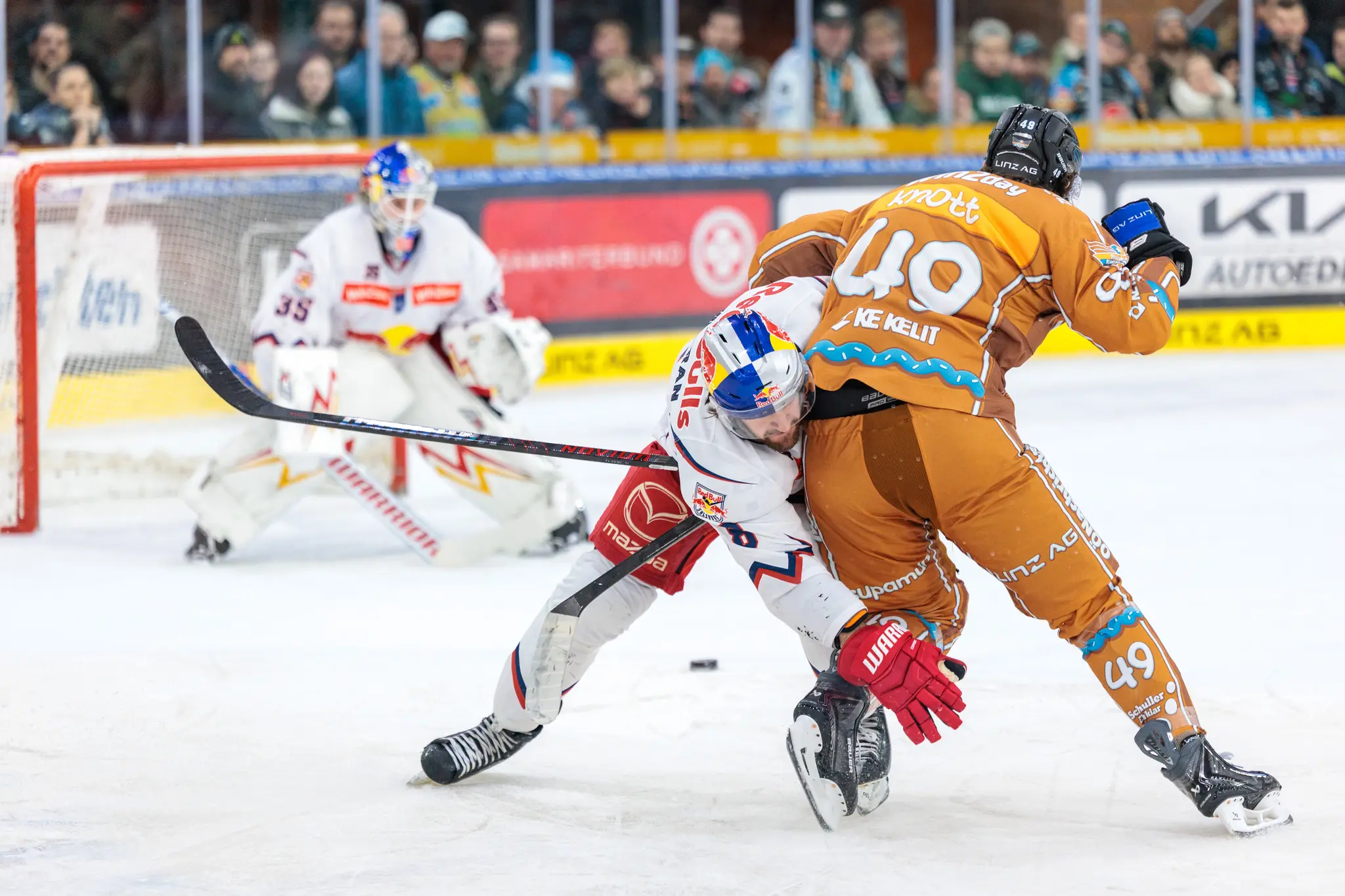 Eishockeyspieler Graham Knott von den Black Wings Linz checkt Salzburgs Robertson in einem intensiven Zweikampf auf dem Eis vor dem Tor