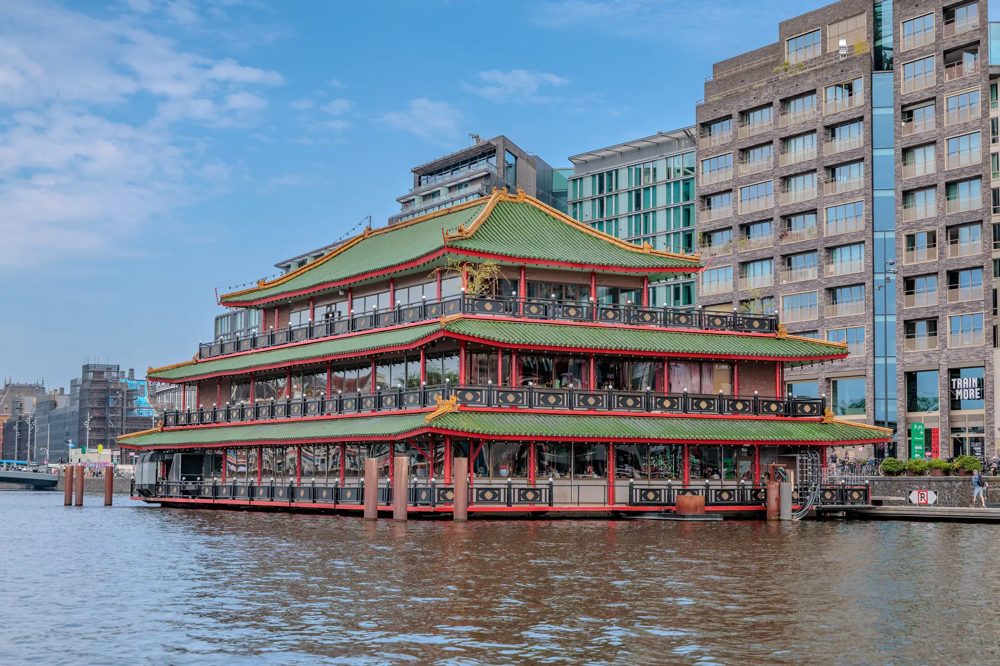 Ein prächtiges chinesisches Schwimmrestaurant mit grünem Pagodendach liegt malerisch auf einem Kanal in Amsterdam, umgeben von städtischen Gebäuden