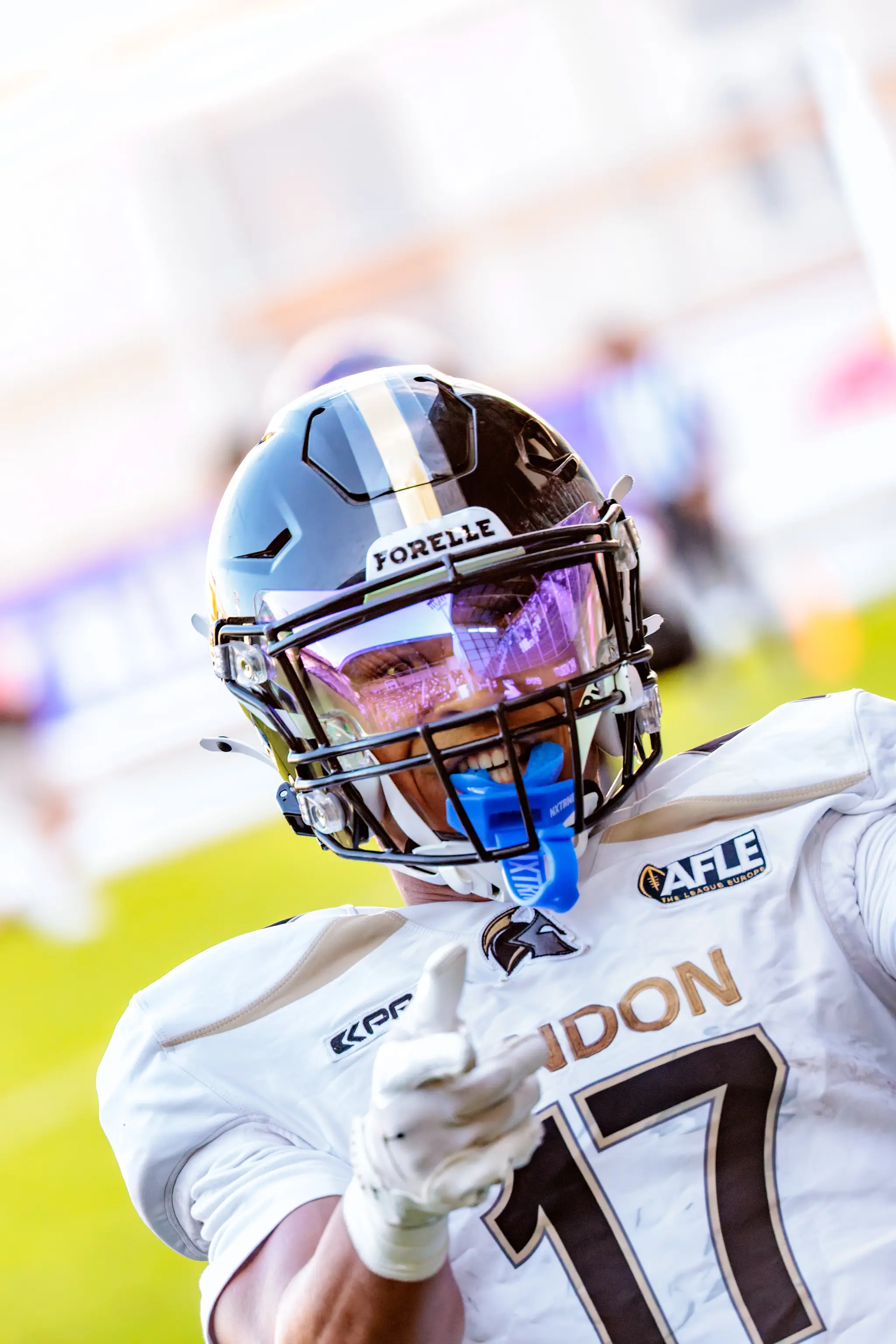 Lachendes Portrait von Spieler Nr. 17 der London Warriors nach dem Touchdown – hinter dem violetten Visier spiegeln sich die Tribünen des Wiener Sport-Club-Stadions.