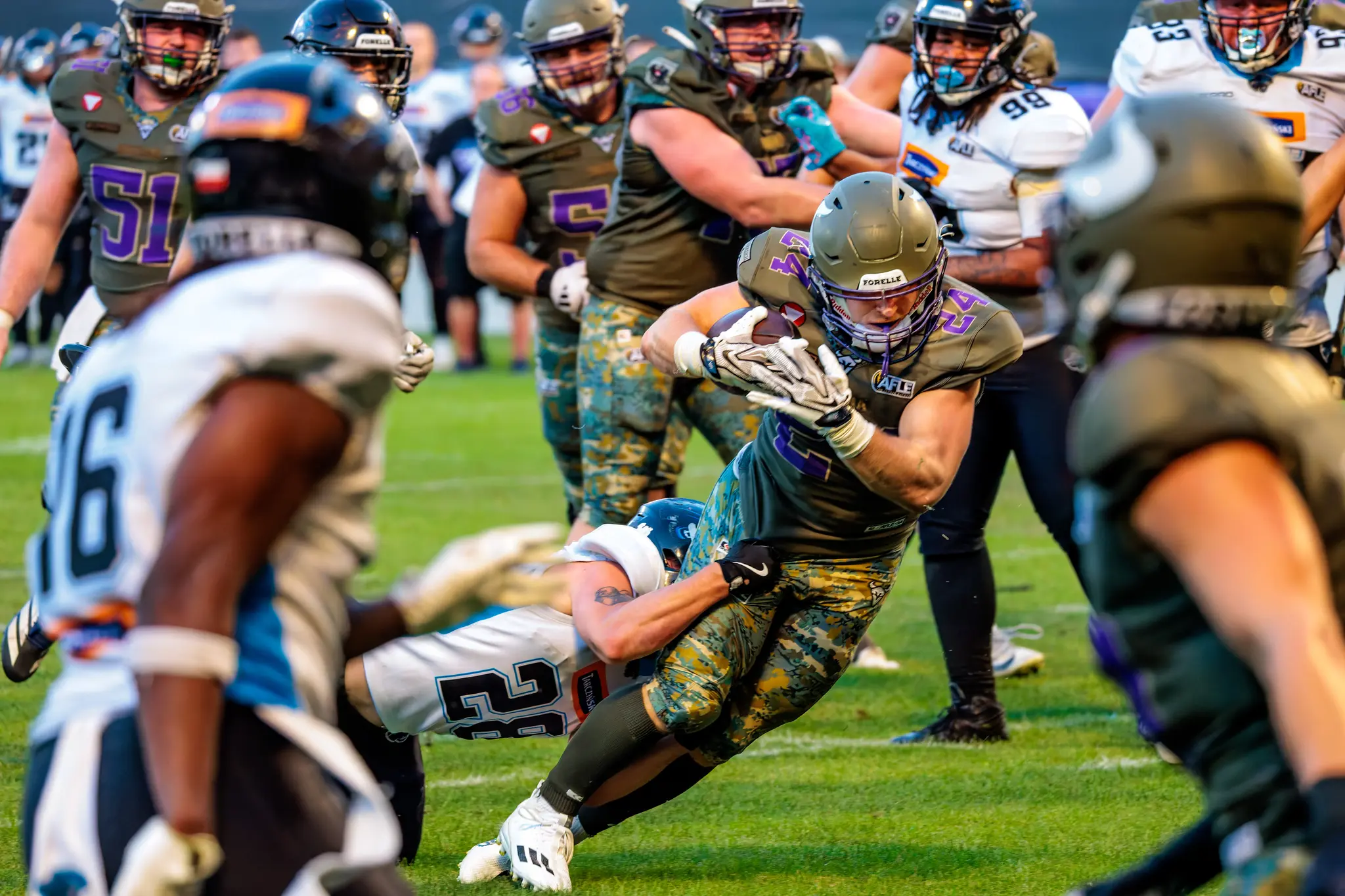 Vikings-Ballträger Karri Pajarinen (Nummer 24) läuft mit gesichertem Football durch die Abwehr, Panthers-Spieler greifen nach seinen Beinen.