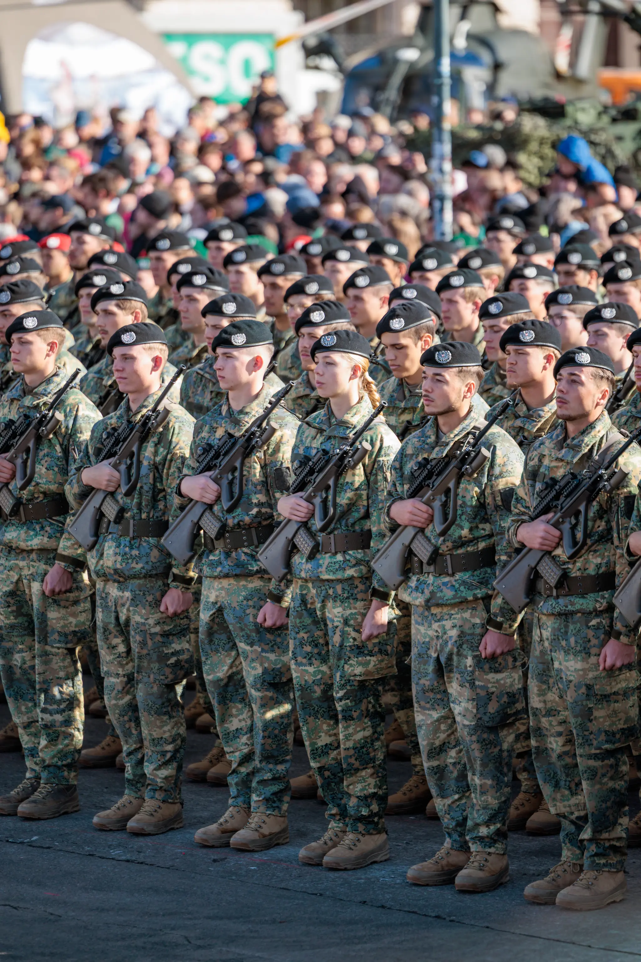 Rekruten mit schwarzen Baretten und Sturmgewehren stehen dicht gedrängt in der Formation, die Blicke nach vorn gerichtet.