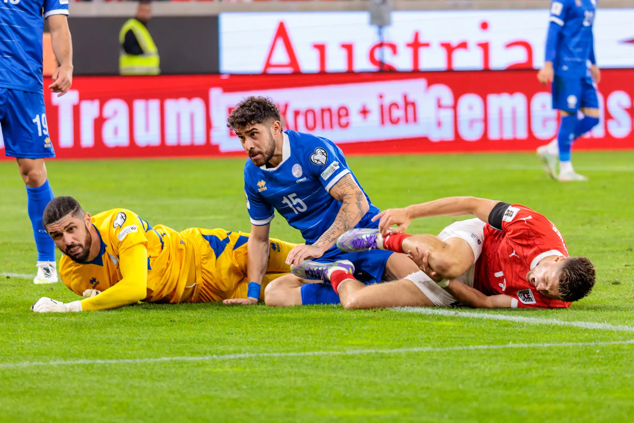 Der österreichische Spieler Christoph Baumgartner liegt nach einem Foul am Boden, mit dem zypriotischen Spieler Christos Shelis und Torwart Fabiano in unmittelbarer Nähe