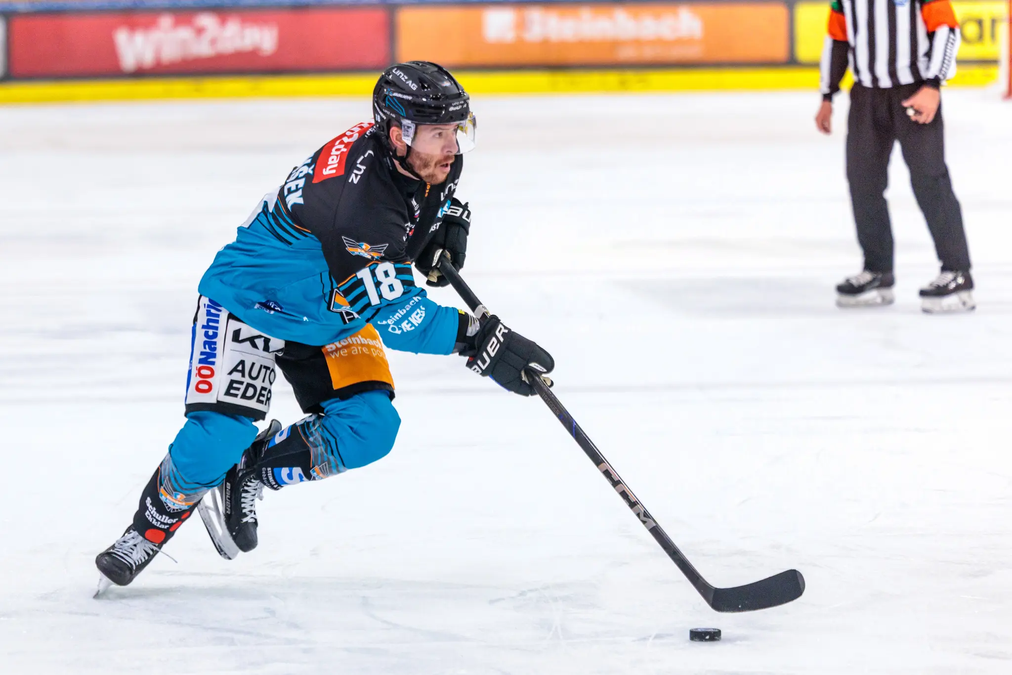 Der Eishockeyspieler Ken Ograjensek von den Black Wings Linz führt in voller Aktion den Puck mit seinem Schläger über das Eis