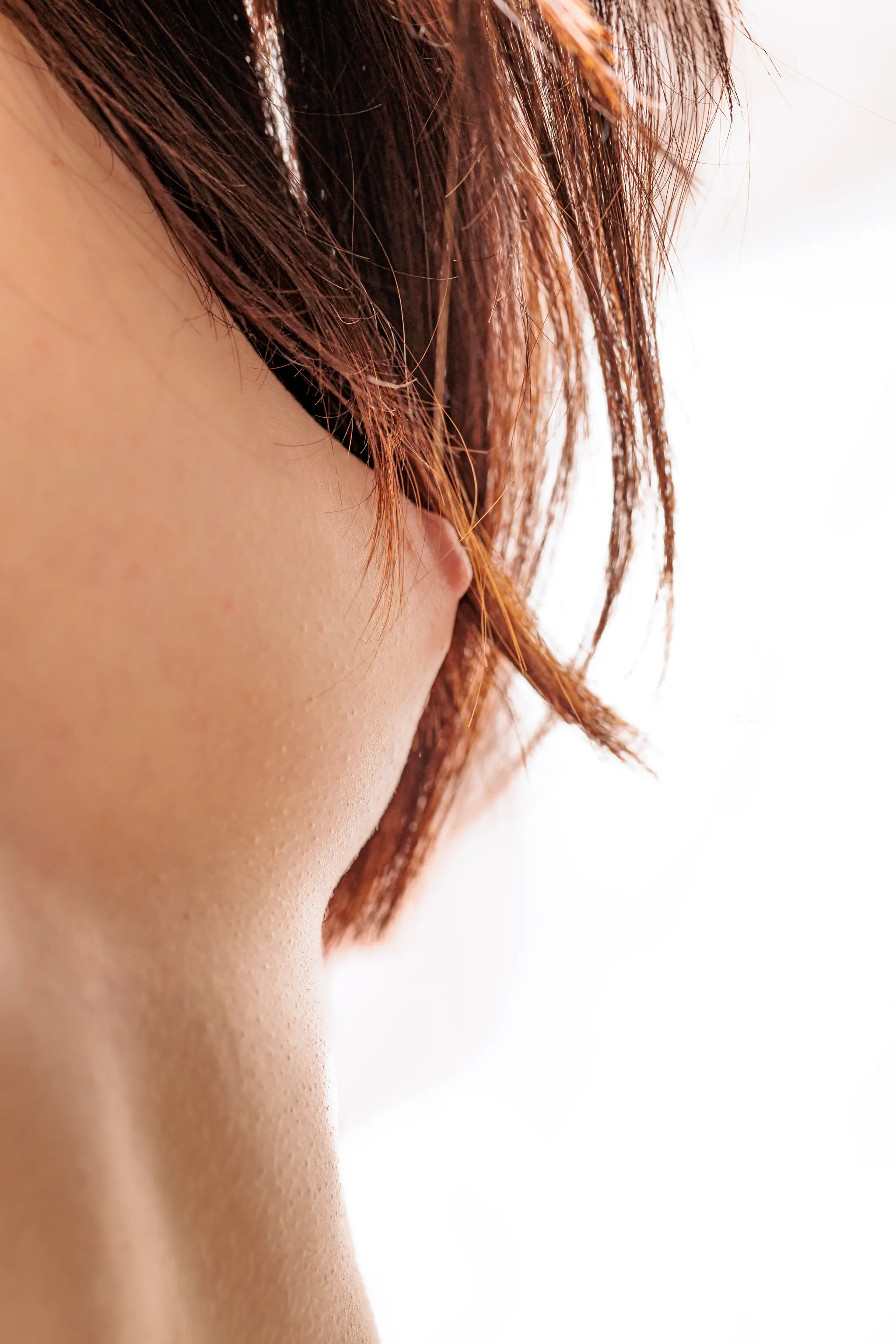 Eine Nahaufnahme der Brust einer Frau, wobei rötlich-braune Haare ihre Brust teilweise verdecken 