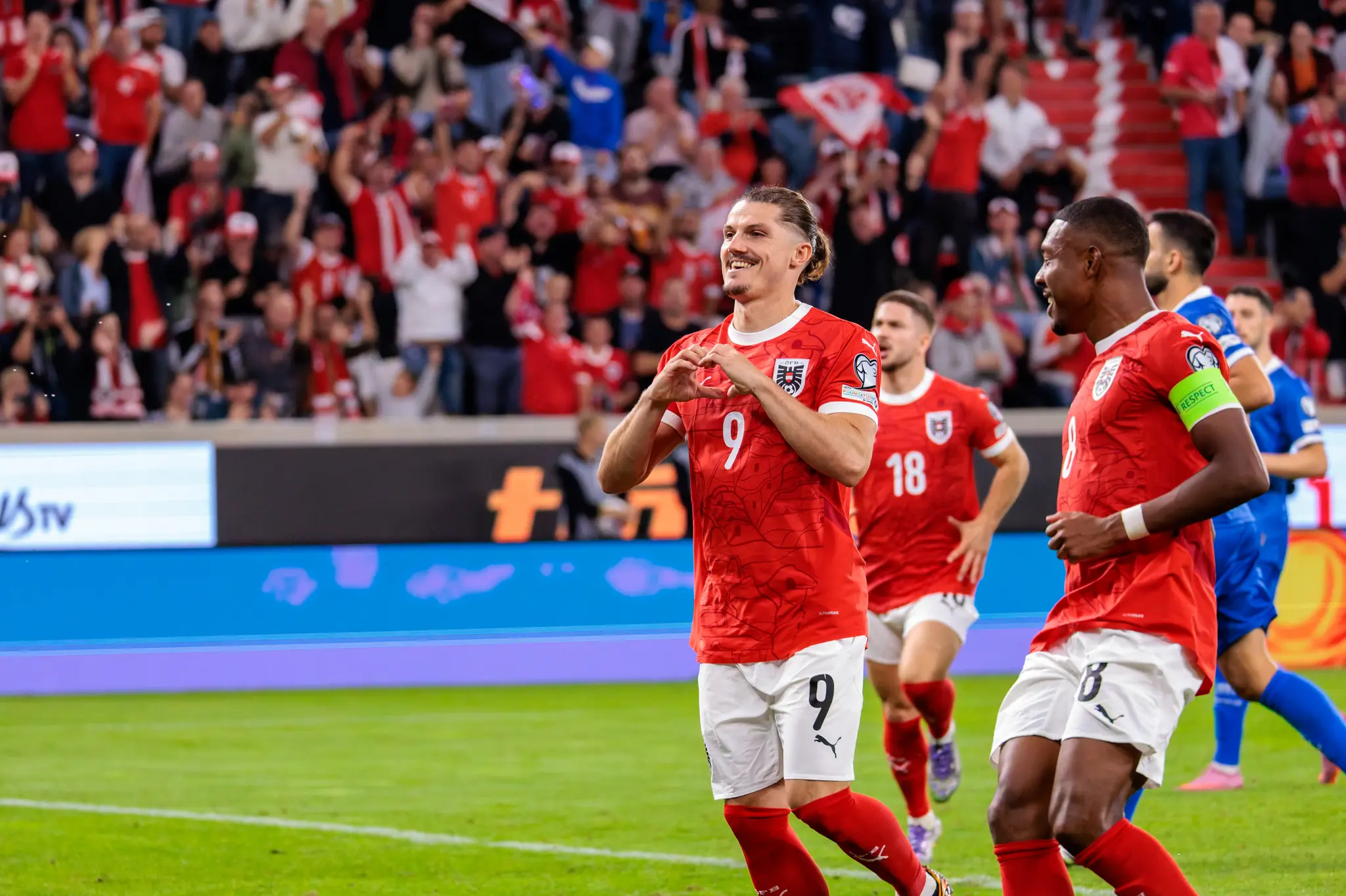 Marcel Sabitzer (Nummer 9) feiert nach dem verwandelten Elfmeter für Österreich mit einer Herzgeste, während sein Teamkollege David Alaba (Nummer 8) daneben steht