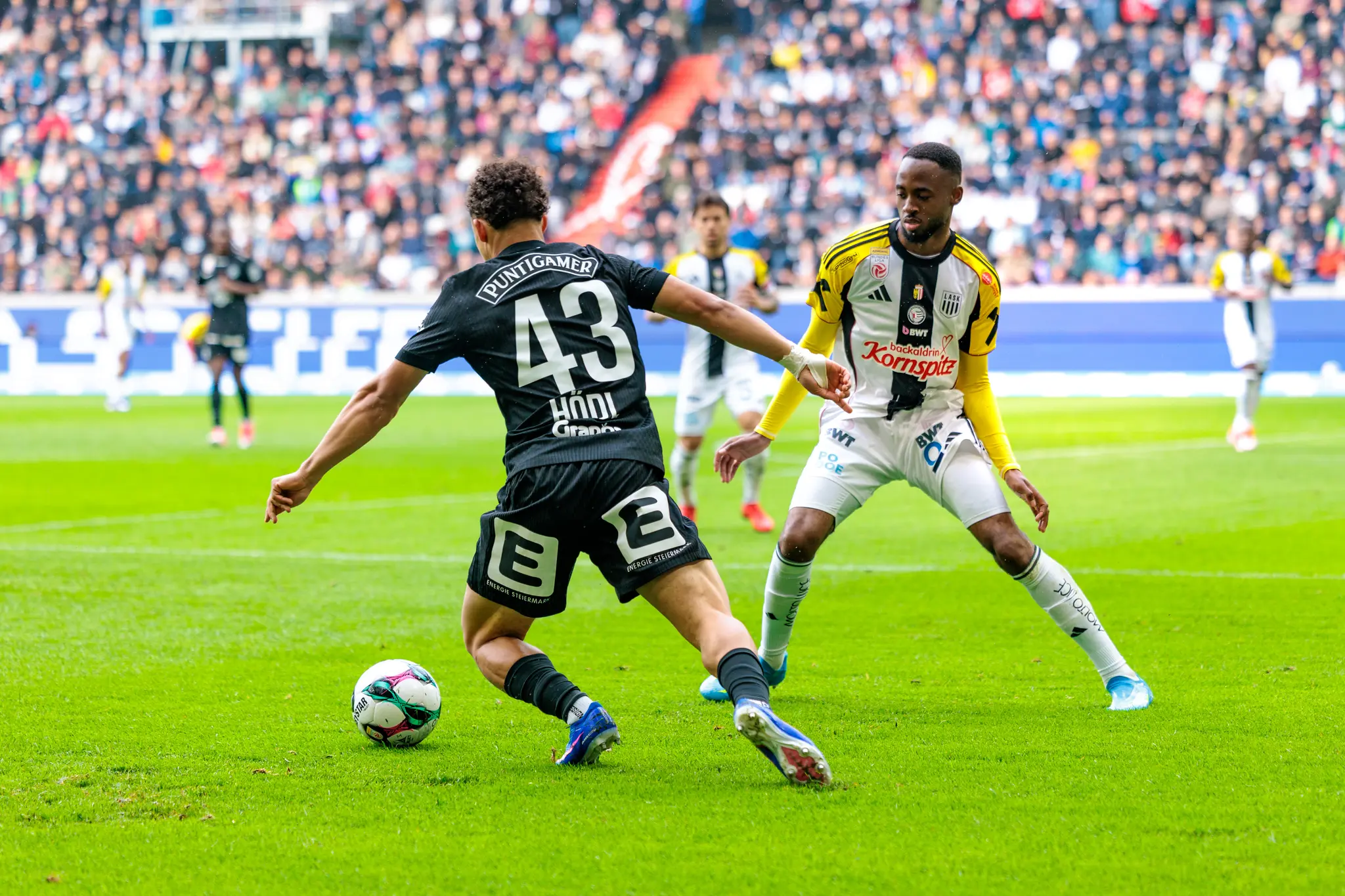 Ein LASK-Spieler sichert den Ball gegen einen Strum Graz-Spieler ab