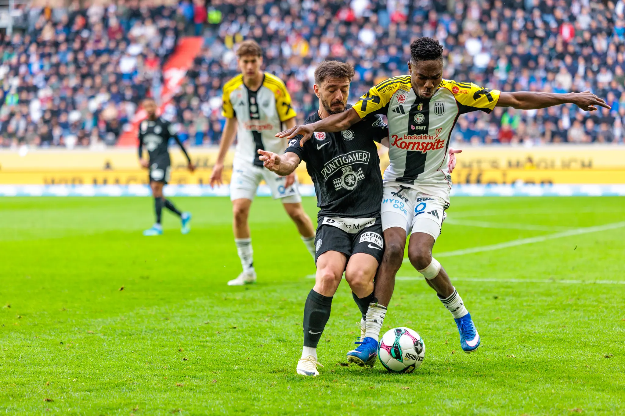 Ein LASK-Spieler versucht im Zweikampf gegen einen Sturm-Graz-Angreifer den Ball zu erobern