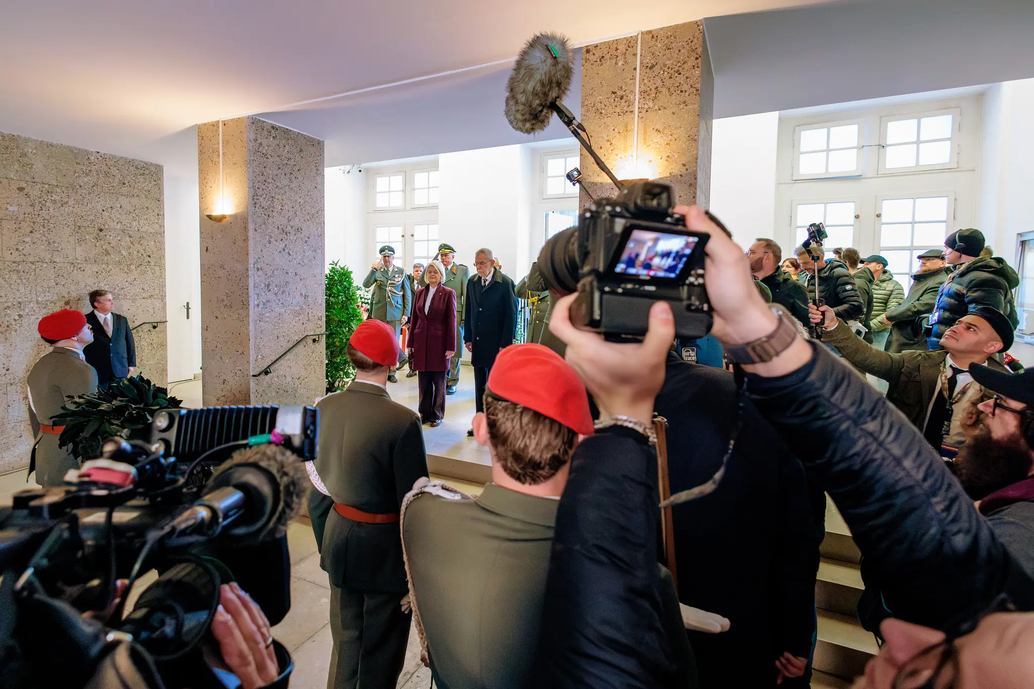 Kamerateams und Fotografen drängen sich im Weiheraum des Äußeren Burgtors, während Bundespräsident Van der Bellen und die Regierungsvertreter zur Kranzniederlegung schreiten.