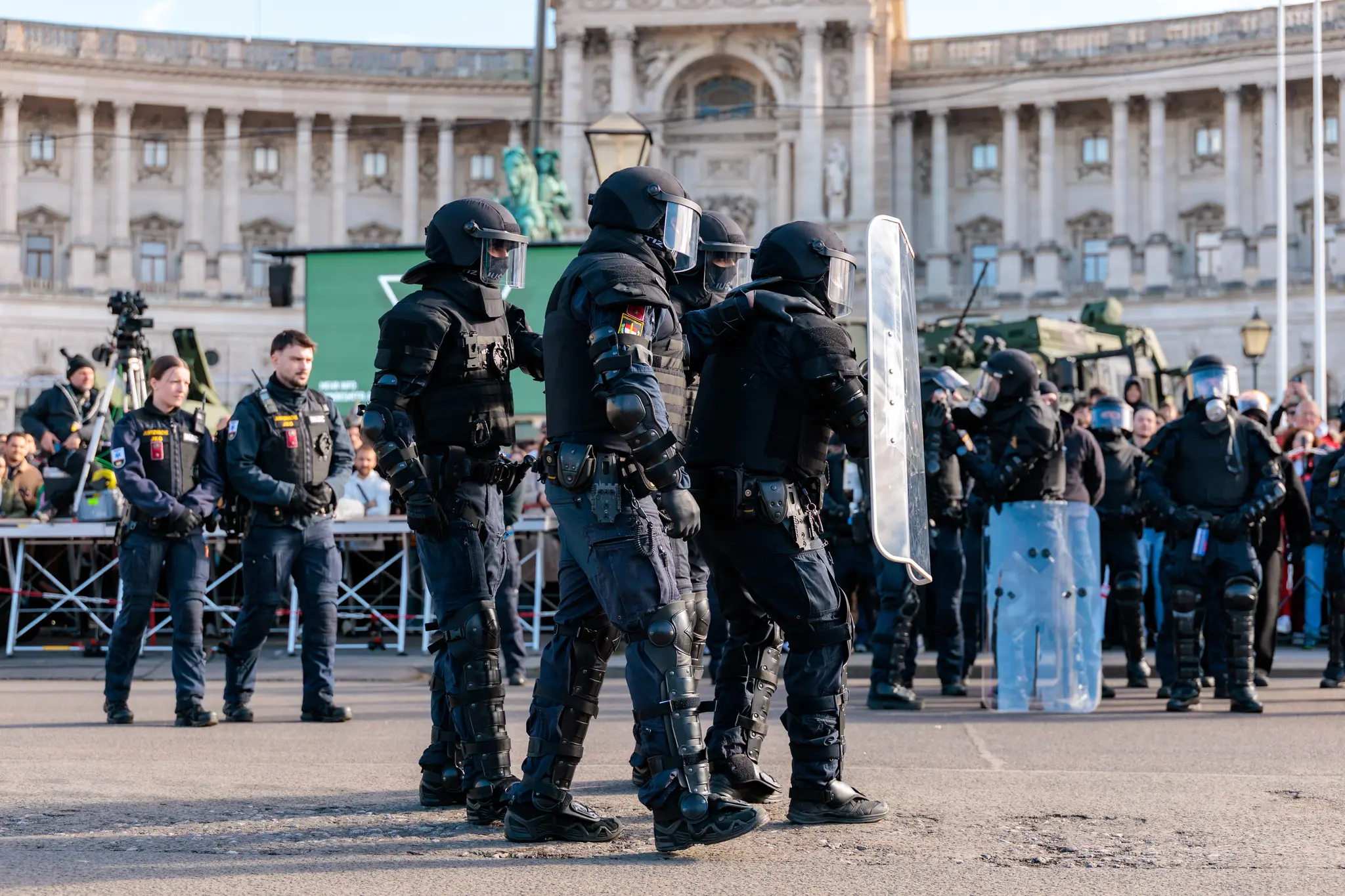 Beamte der Justizwache in schwerer Schutzausrüstung mit Helmen und Schilden stehen in einer Reihe vor der Hofburg.