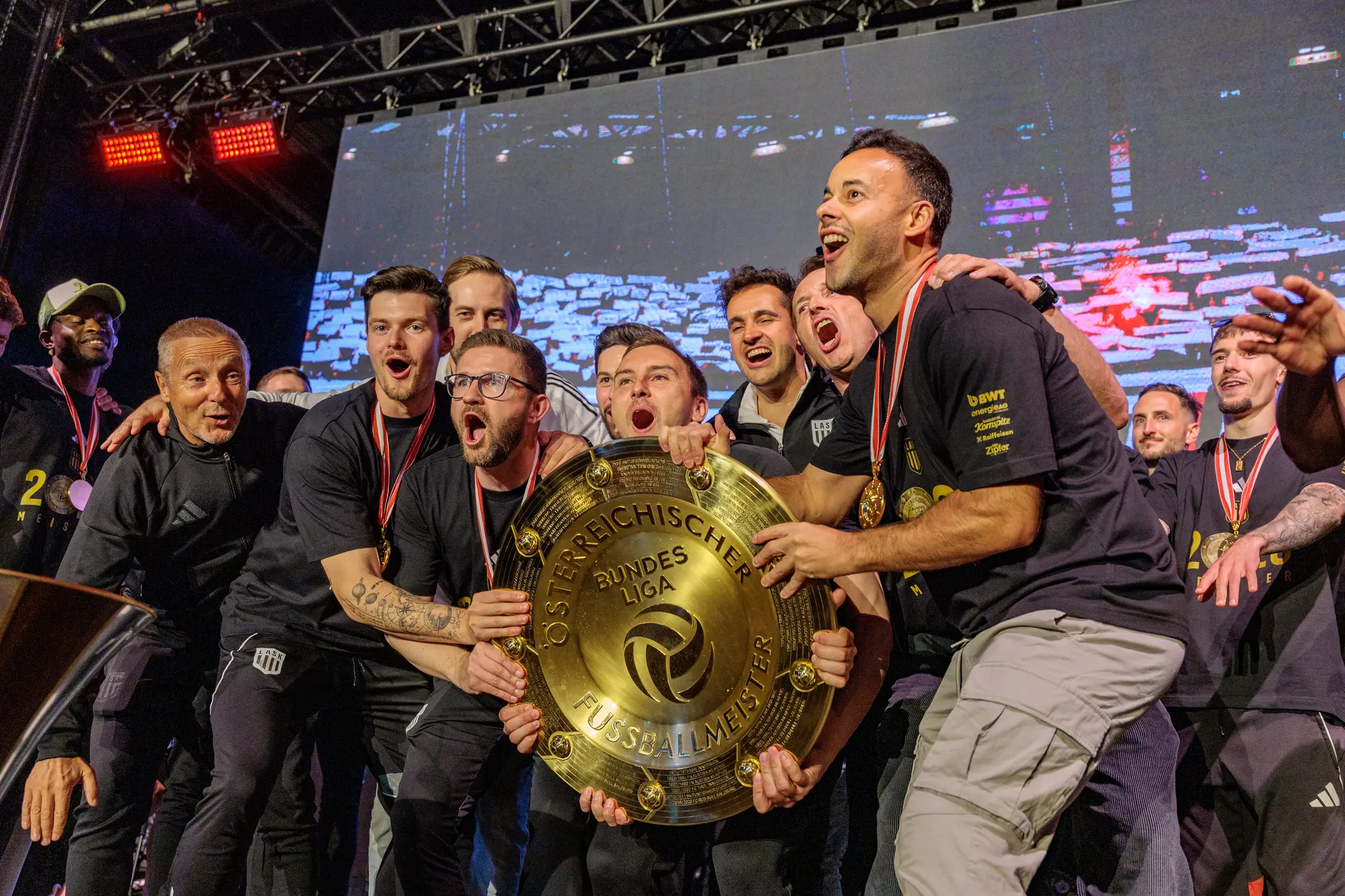 Die Spieler des LASK halten gemeinsam den goldenen Meisterteller bei ihrer emotionalen Siegerehrung auf der Bühne hoch