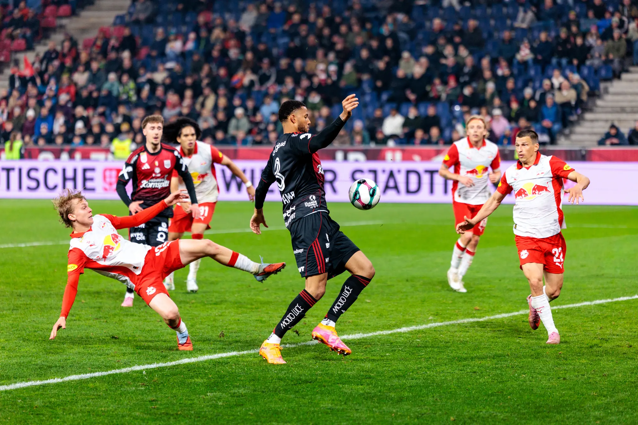 Ein LASK-Spieler führt einen intensiven Zweikampf gegen Spieler von Red Bull Salzburg während eines Bundesliga-Spiels