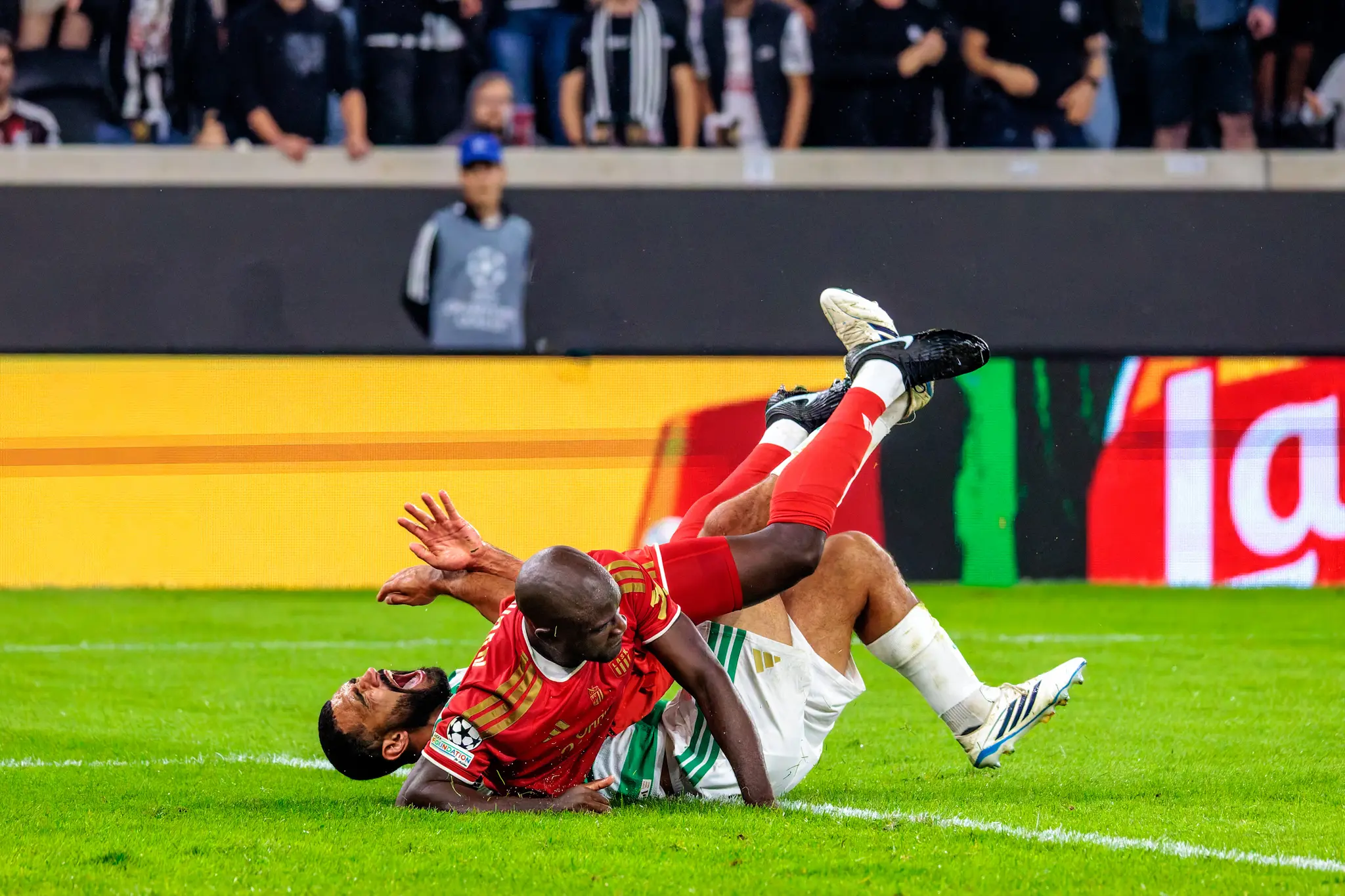 Zu Fall gebracht: Mbuyamba und sein Gegenspieler stürzen nach dem Zweikampf ineinander verschlungen zu Boden und landen hart auf dem nassen Rasen.