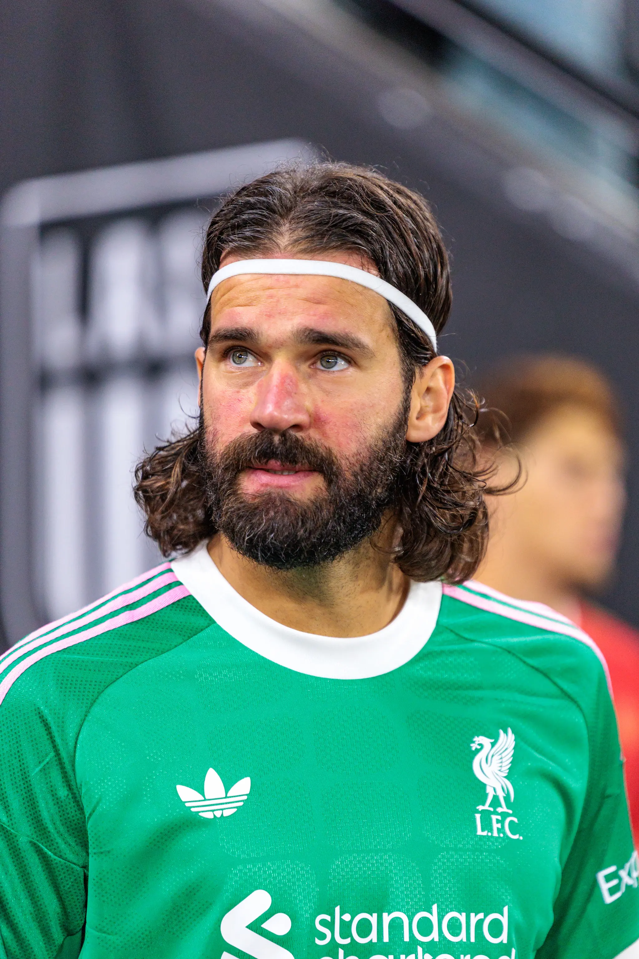 Ein Torwart des FC Liverpool im grünen Trikot blickt vor dem Anpfiff nach oben, dahinter liegt das abgedunkelte Stadion.