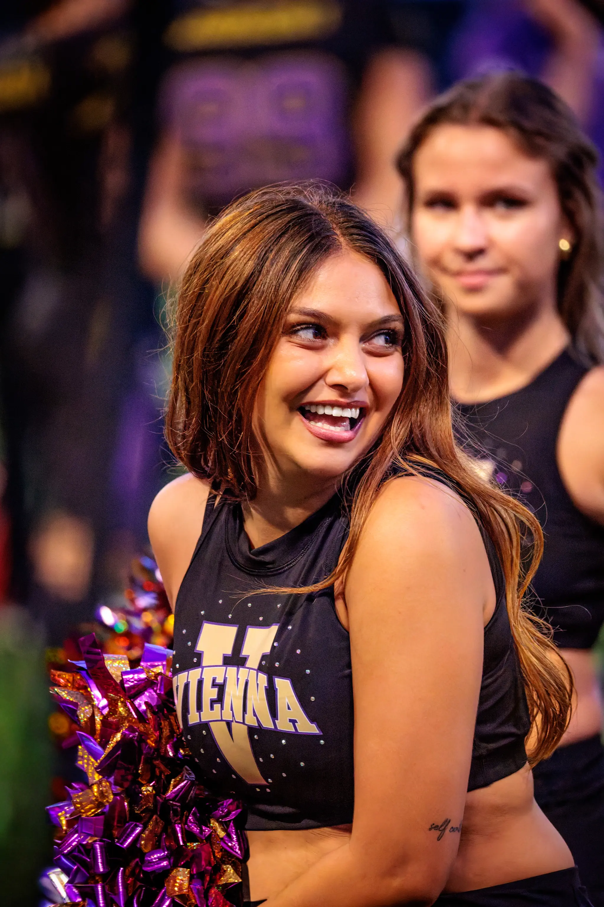 Ein Lachen, das ansteckt: Eine Tänzerin des Vienna Vikings Spirit Squad blickt verschmitzt zur Seite, ihre Kollegin grinst hinten mit.