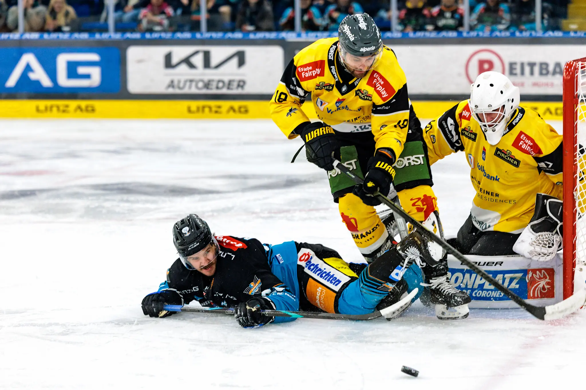 Intensive Spielszene beim Eishockey, bei der der Linzer Stürmer Travis Barron nach einem Zweikampf vor dem Tor des HC Pustertal zu Fall kommt