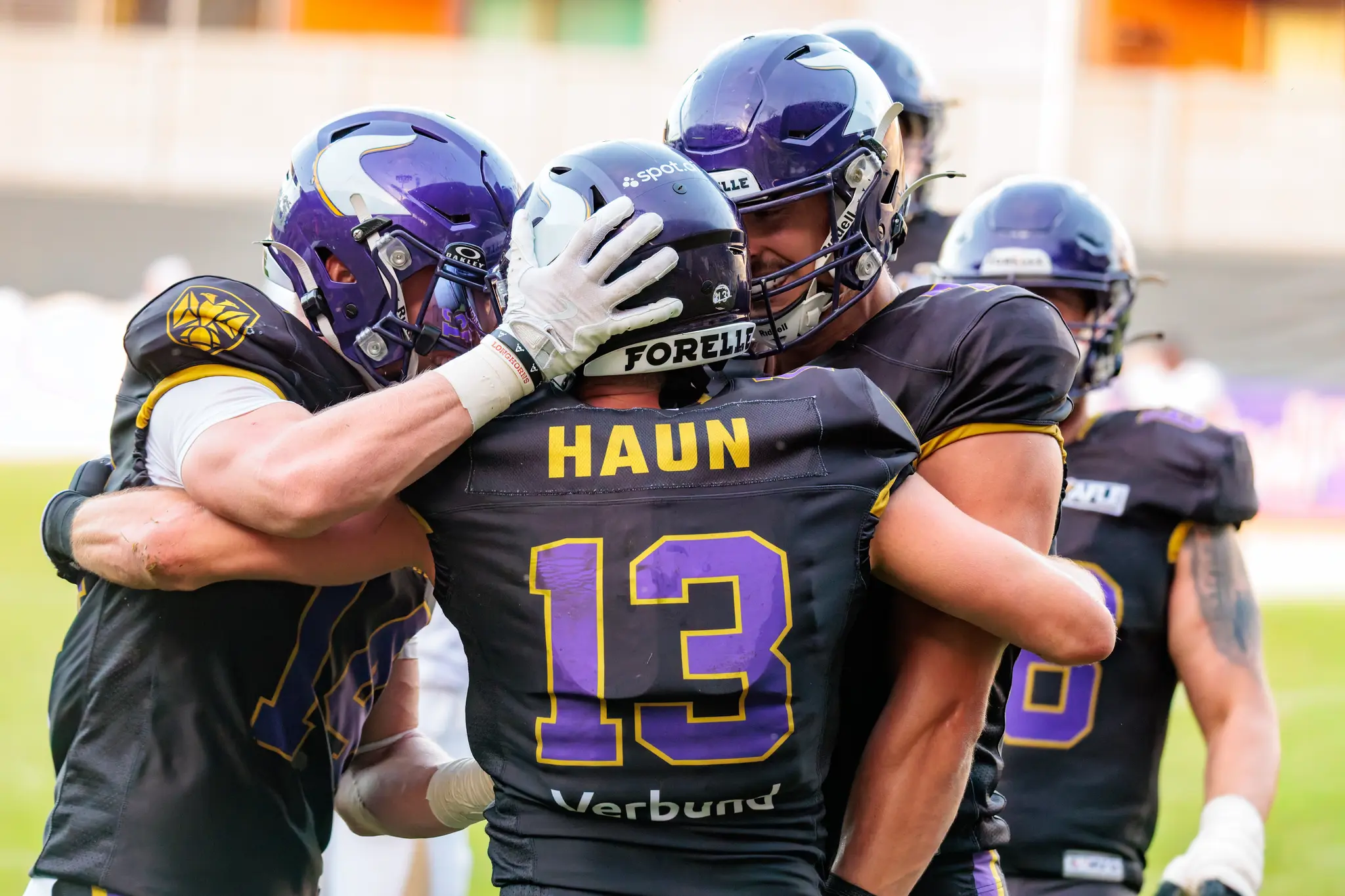 Philipp Haun (13) wird nach seinem Touchdown von Teamkollegen der Vienna Vikings umarmt – Jubel auf dem Rasen im Wiener Sport-Club-Stadion.