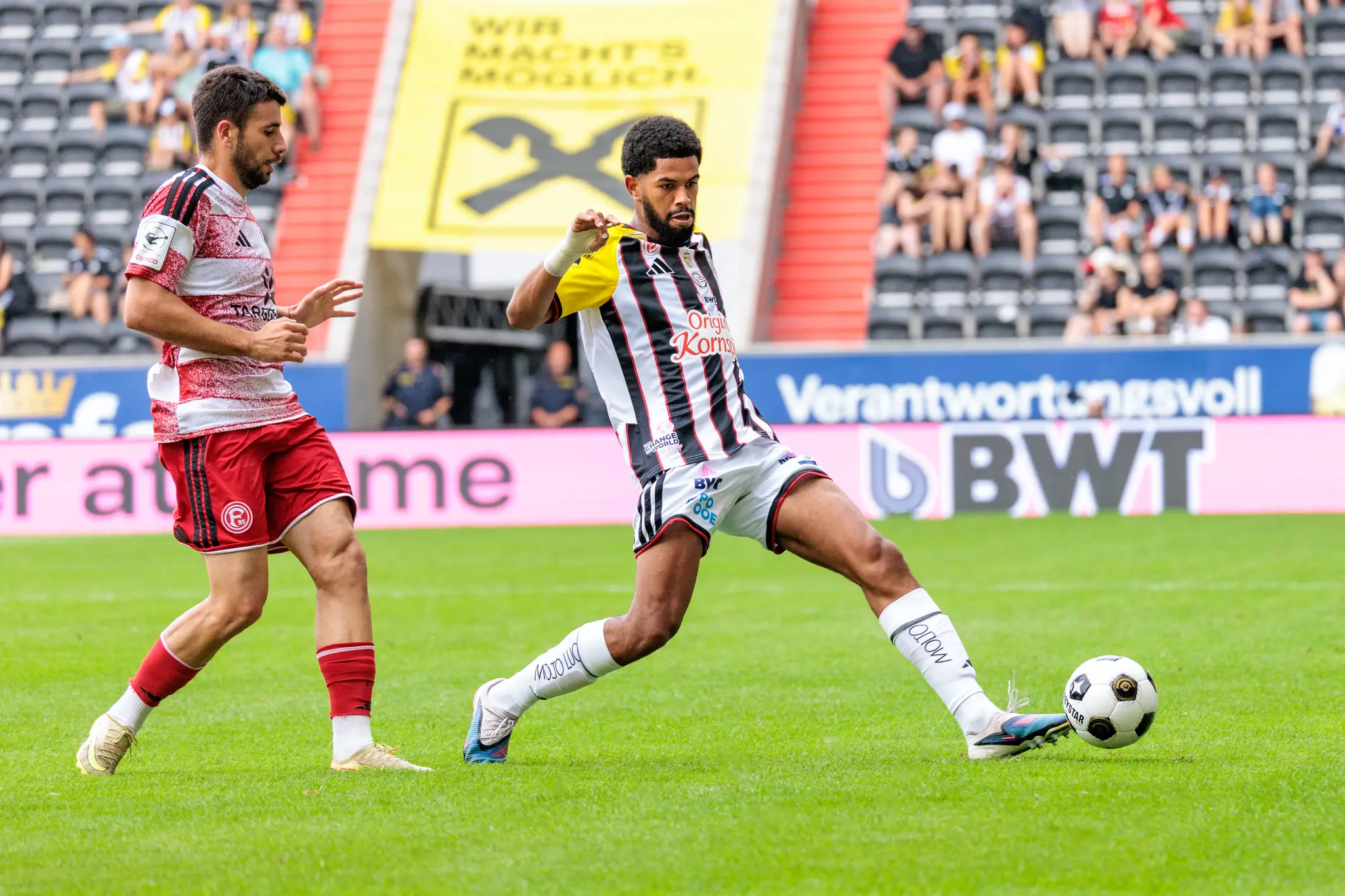 LASK-Spieler spielt einen präzisen Pass in die Mitte, dynamische Bewegung in der 66. Minute.