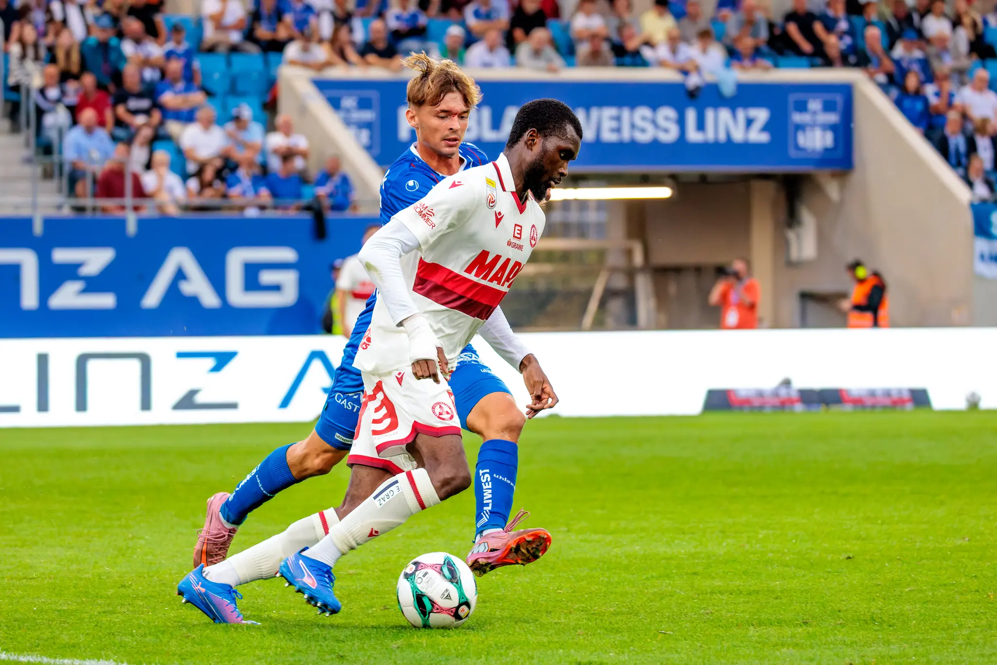 Sadik Fofana vom Grazer AK dribbelt am Ball, während Simon Seidl vom FC Blau-Weiß Linz versucht, ihm den Ball abzunehmen