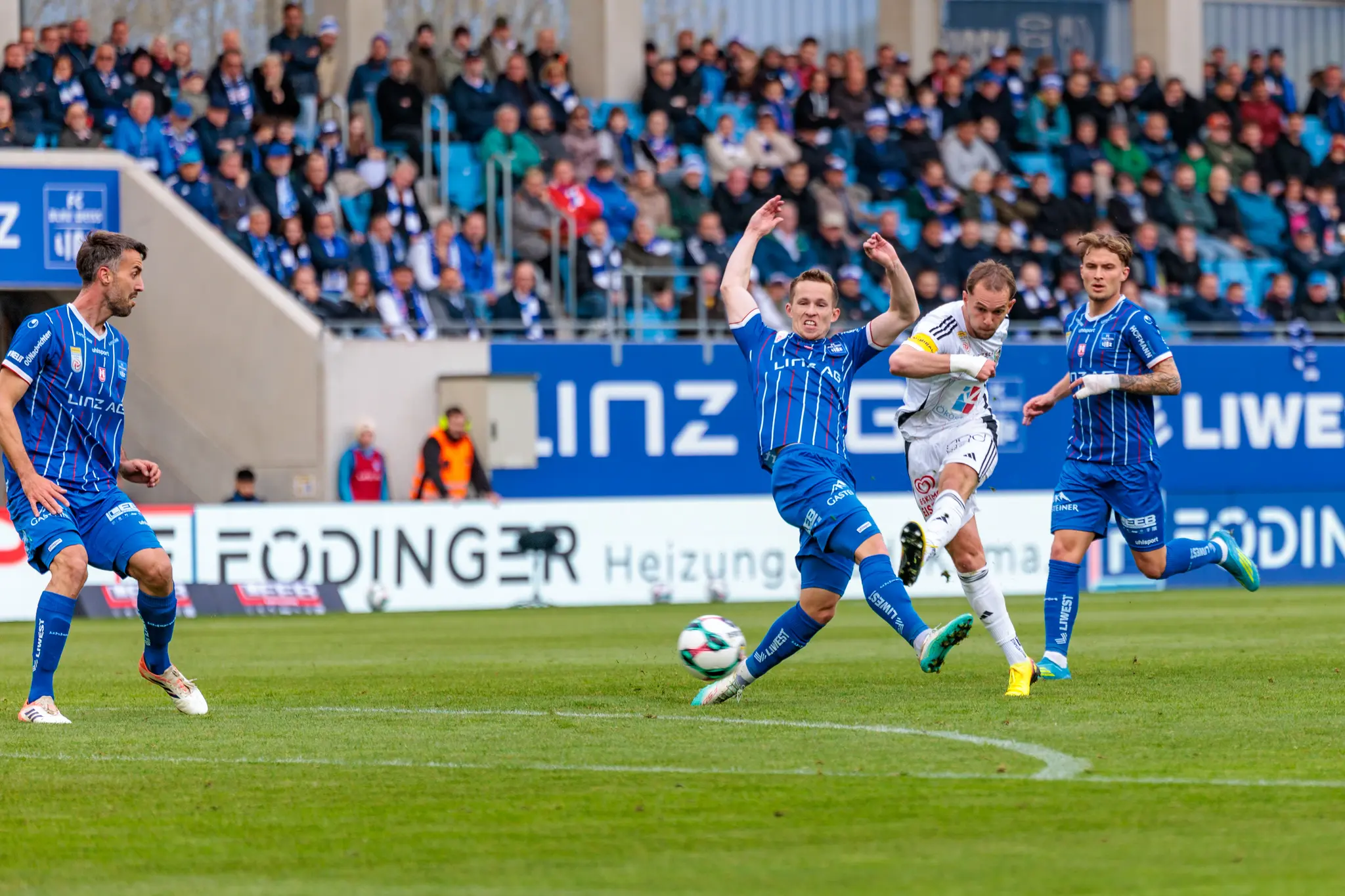 Ein Spieler des FC Blau-Weiß Linz versucht einen Torschuss eines Gegenspielers vor den Augen der Zuschauer zu blockieren
