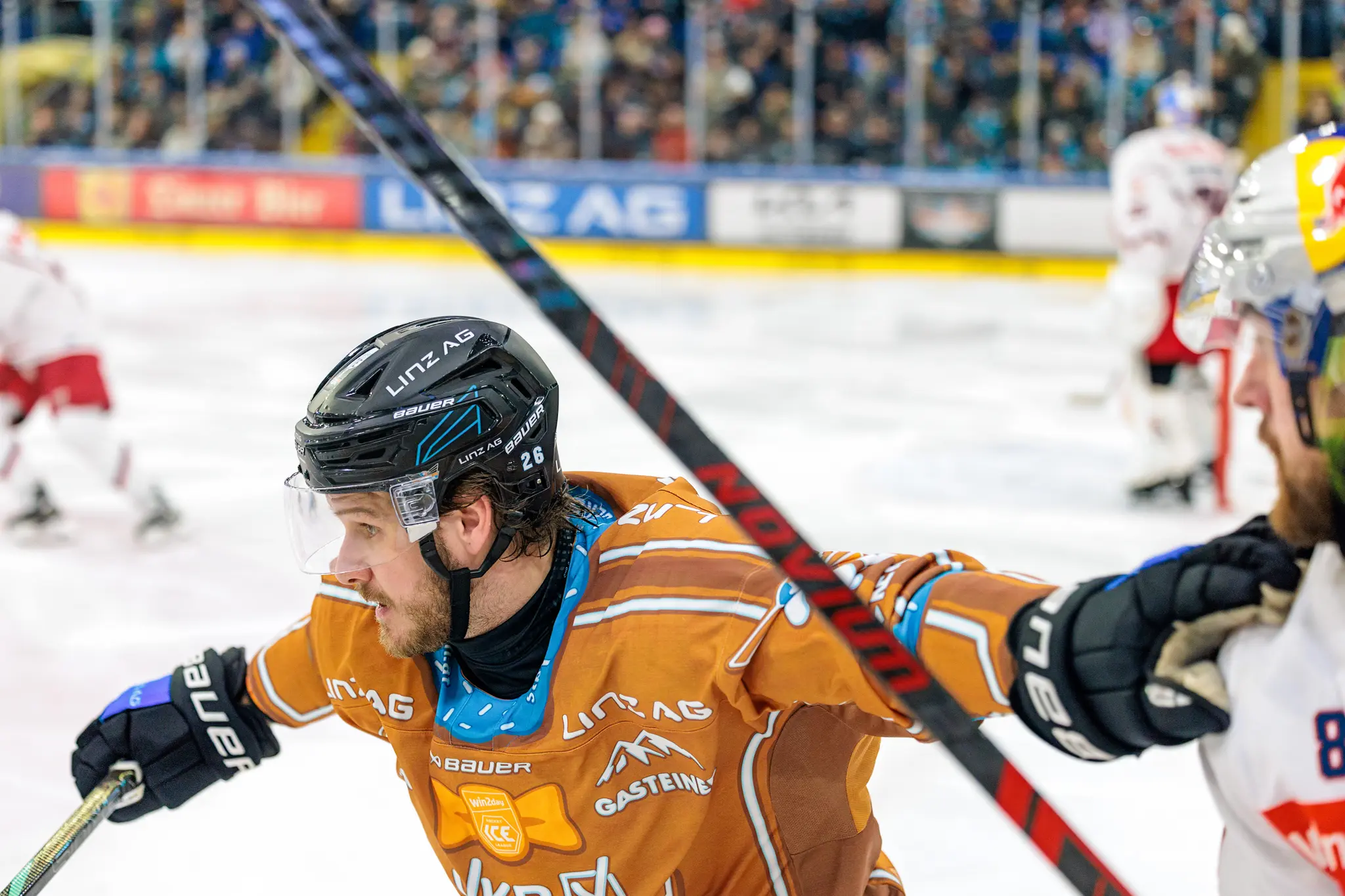 Der Eishockeyspieler Barron der Black Wings Linz mit der Nummer 26 im orangefarbenen Trikot während eines Spiels auf dem Eis