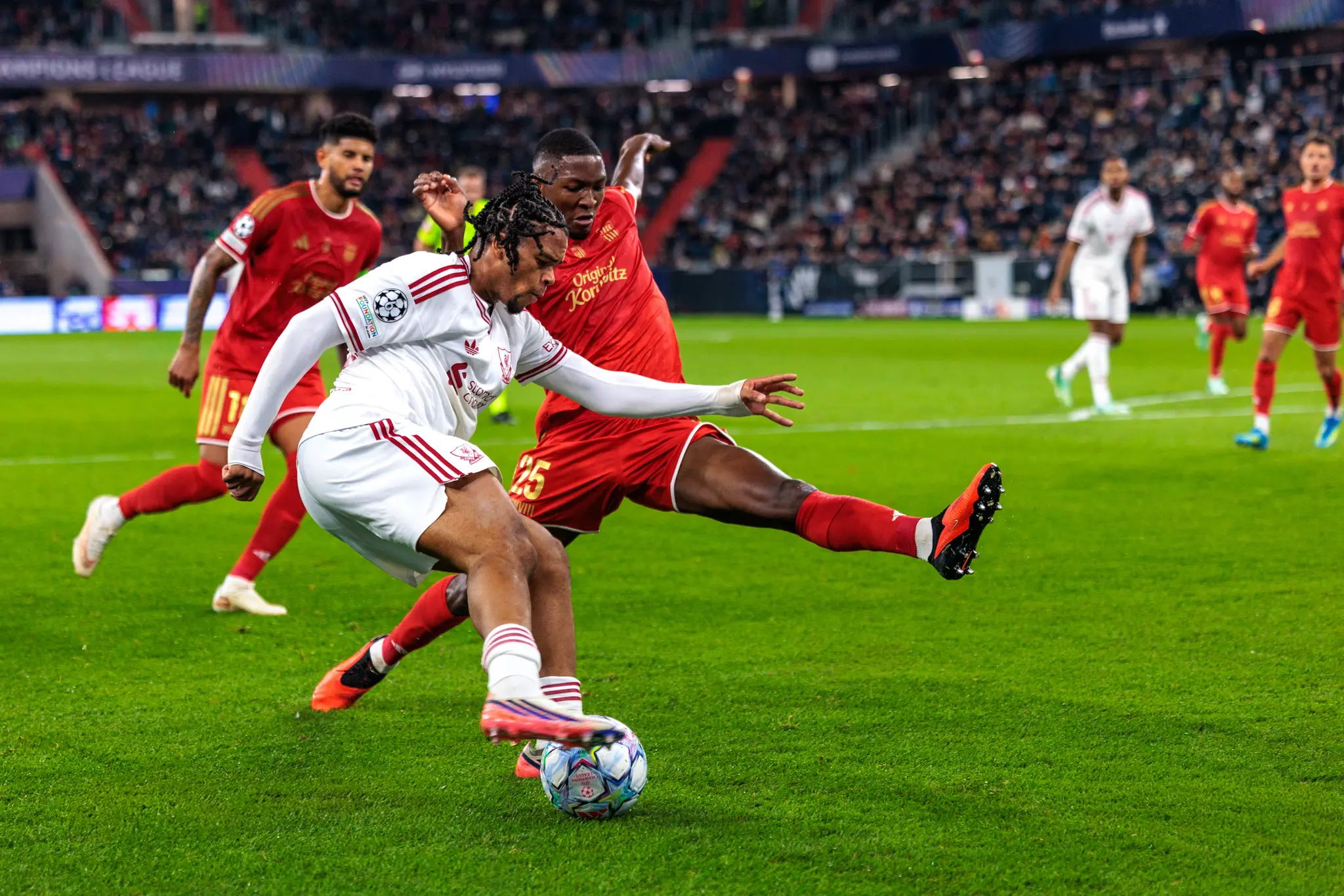Yvan Dibango (25) spielt mit ausgestrecktem Bein den Ball, ein Liverpooler Spieler wirft sich im Zweikampf dazwischen.