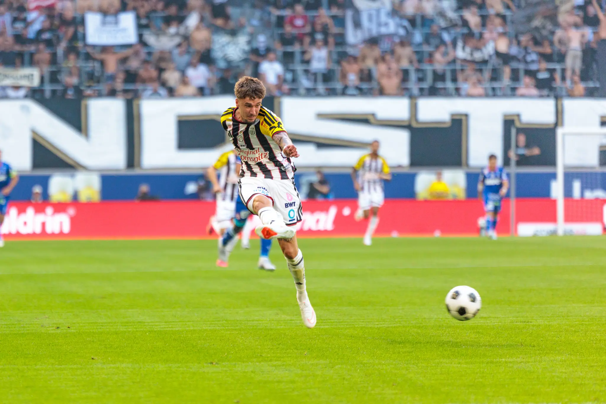 LASK-Spieler schießt auf das Tor im Angriff, der Ball fliegt in Richtung des vom GAK-Torhüter verteidigten Tores