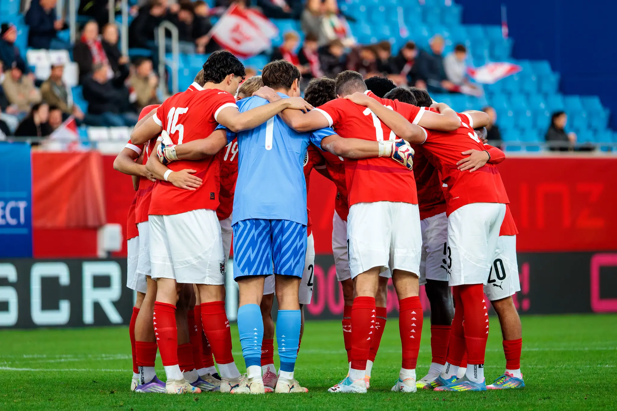 Die Spieler der österreichischen U21-Nationalmannschaft stehen von hinten gesehen in einem engen Kreis zusammen und umarmen sich beim Team-Huddle