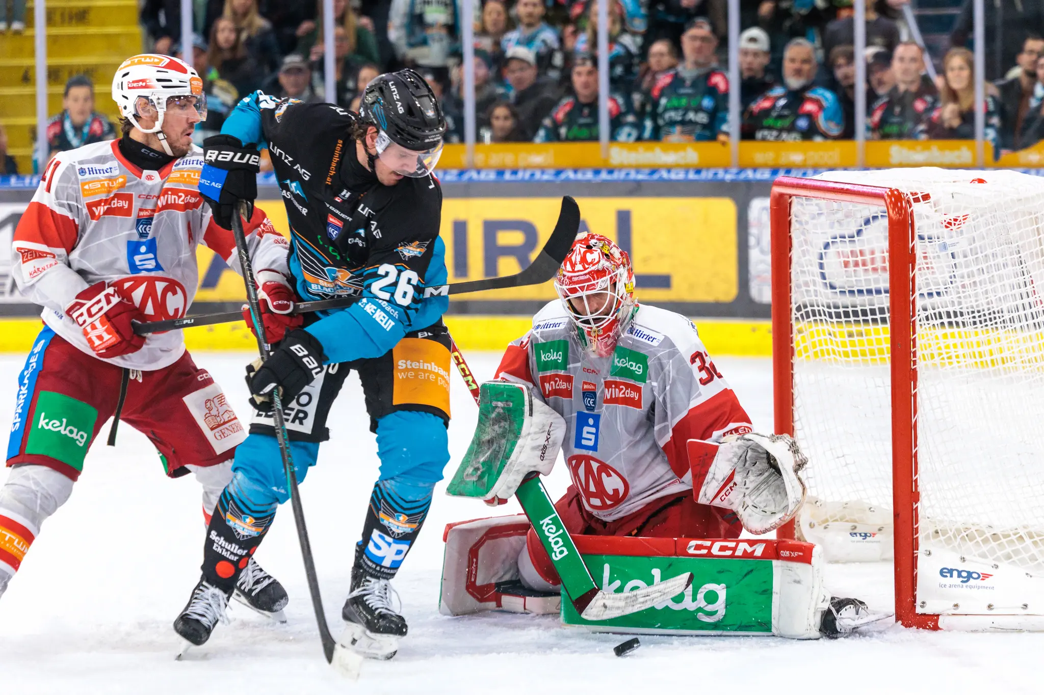Der Stürmer der Steinbach Black Wings, Travis Barron, versucht in einer intensiven Spielszene den Puck am KAC-Goalie Sebastian Dahm vorbei ins Tor zu schießen