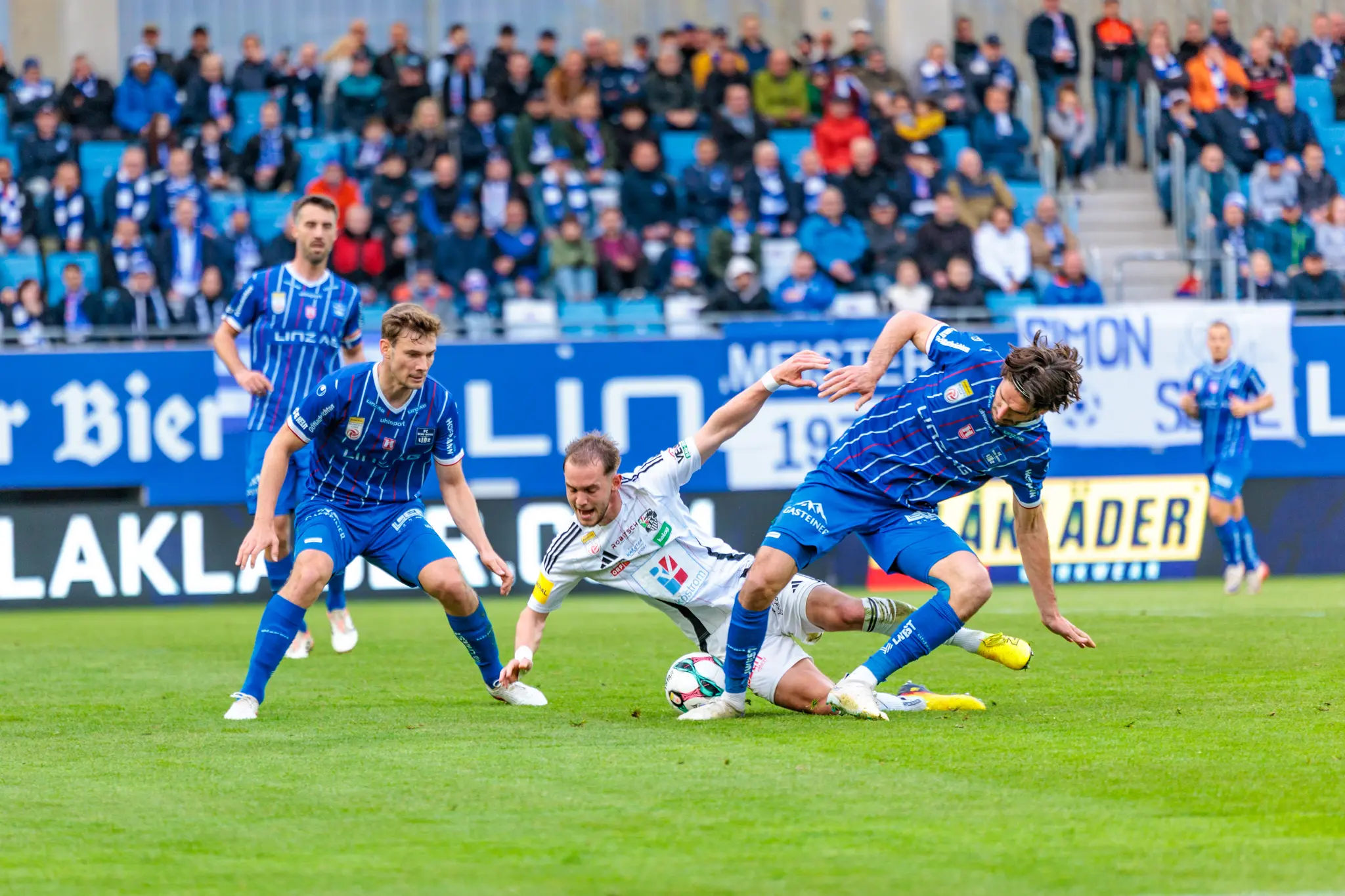 Ein Spieler des Wolfsberger AC geht im intensiven Zweikampf um den Ball gegen einen Gegenspieler von Blau-Weiß Linz