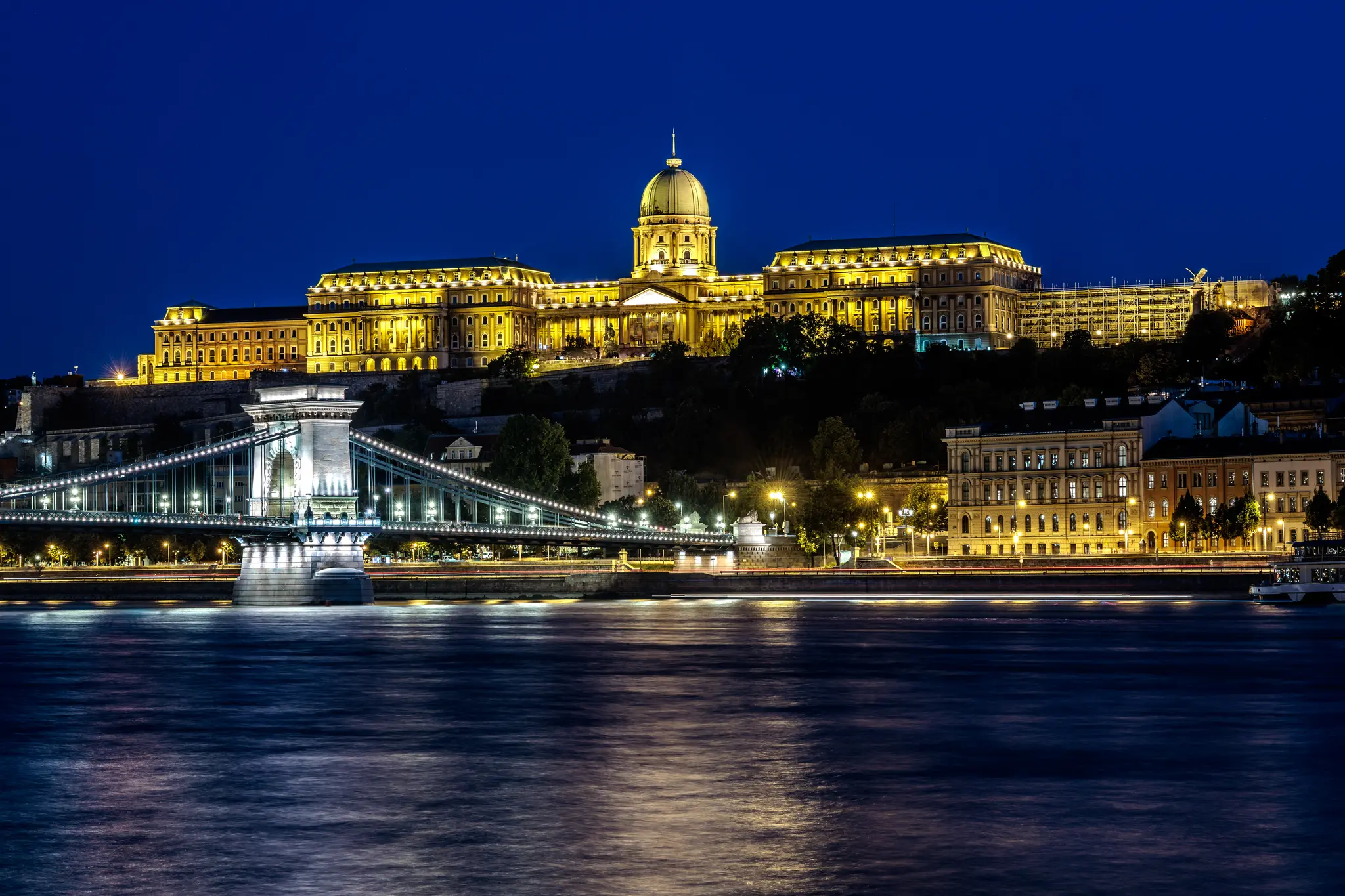 Nachtansicht der beleuchteten Kettenbrücke und des Budaer Burgpalastes über der Donau in Budapest. 