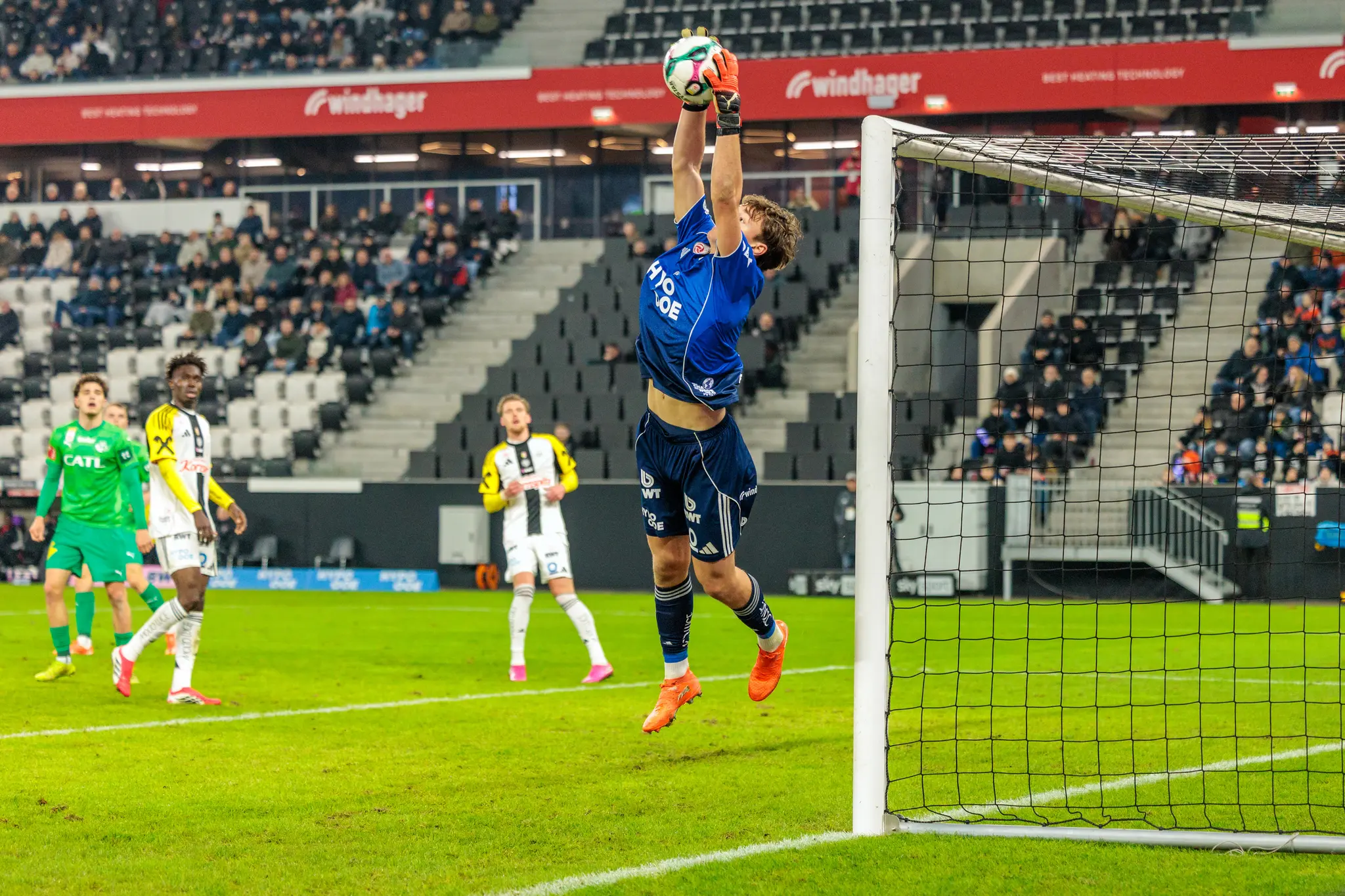 Der LASK-Torwart Lukas Jungwirth pariert einen Ball mit einem Sprung hoch in die Luft nahe dem Torpfosten