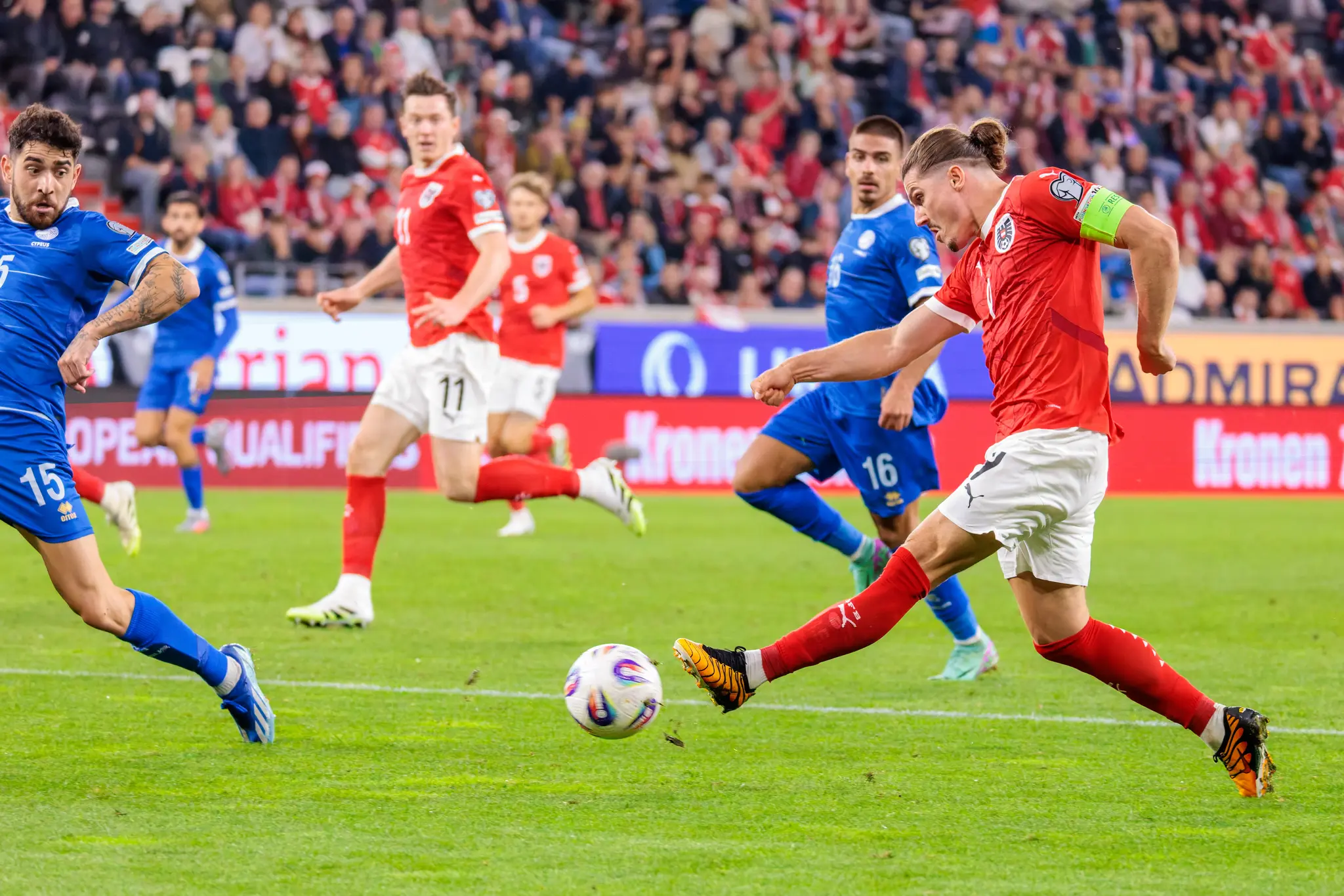 Marcel Sabitzer von Österreich schießt den Ball während eines Fußballspiels, beobachtet von zwei Spielern Zyperns
