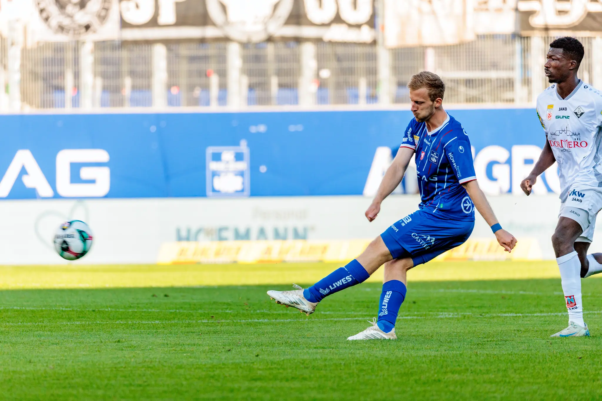 Thomas Goiginger vom FC Blau-Weiß Linz bei einem kraftvollen Flanke im Bundesligaspiel gegen den SCR Altach, während ein Gegenspieler die Szene beobachtet