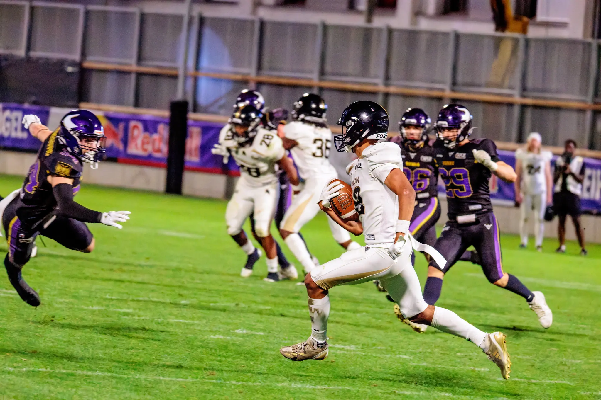 Ein Ballträger der London Warriors sprintet mit dem Ball davon, gejagt von Zoltan Golita (26) und Paul Kriener (29) – von links stürmt ein weiterer Verteidiger der Vienna Vikings heran, offene Passage im Schlussviertel.