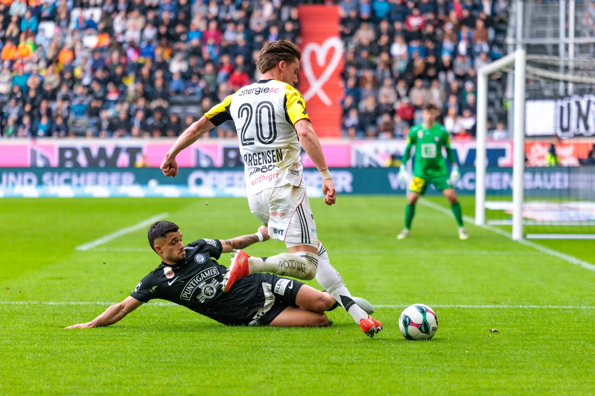 Ein Sturm-Spieler führt ein rutschendes Tackling gegen den LASK-Angreifer Jörgensen aus
